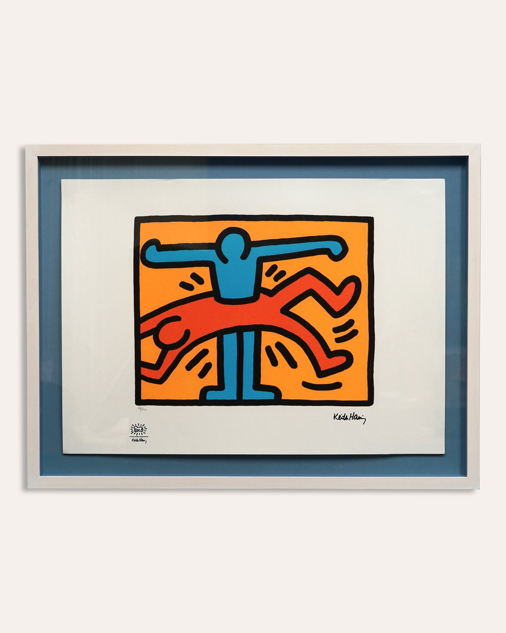 A framed and matted Keith Haring limited edition signed print featuring colorful abstract figures on a white background.