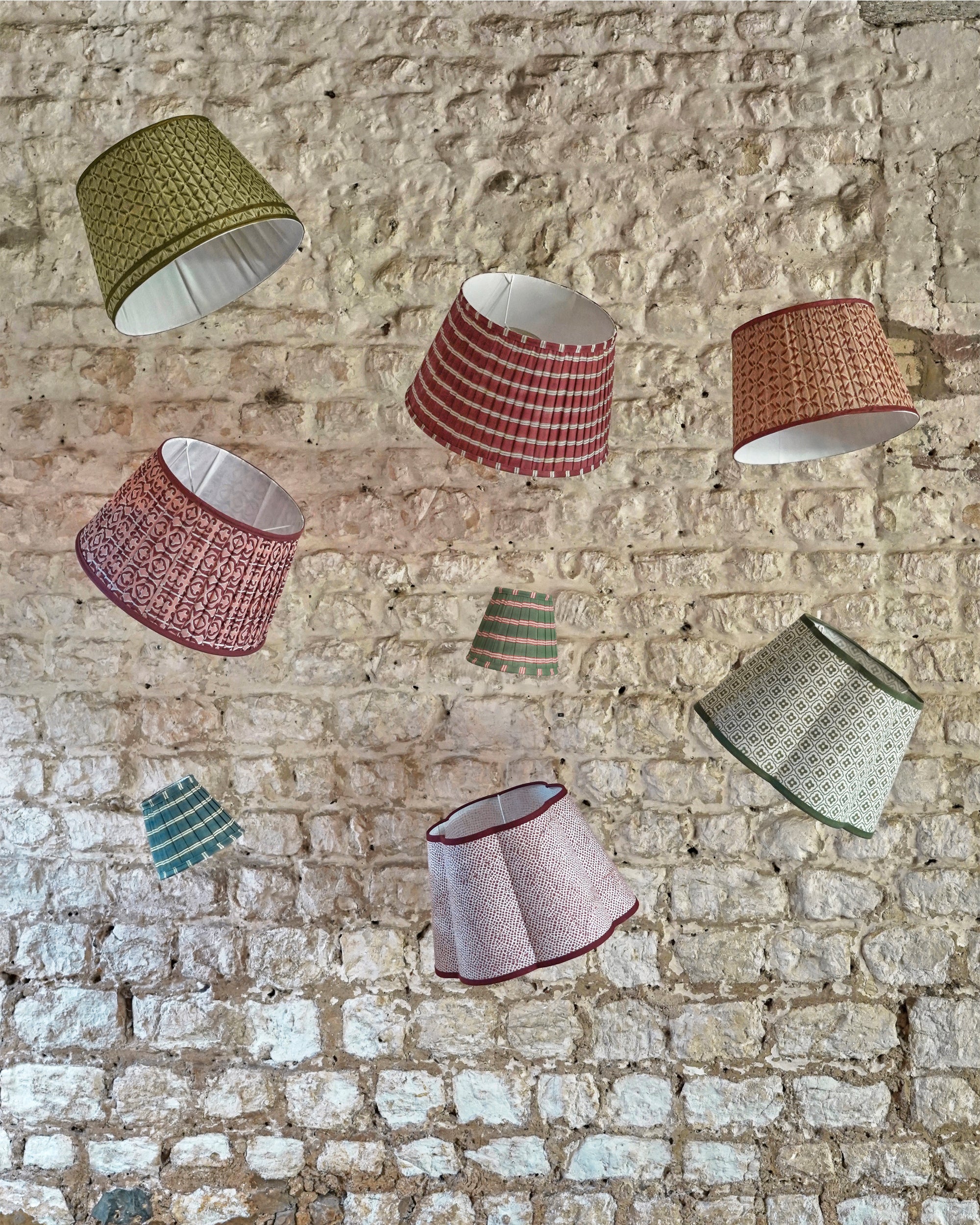 Colourful lampshades hanging against a stone wall