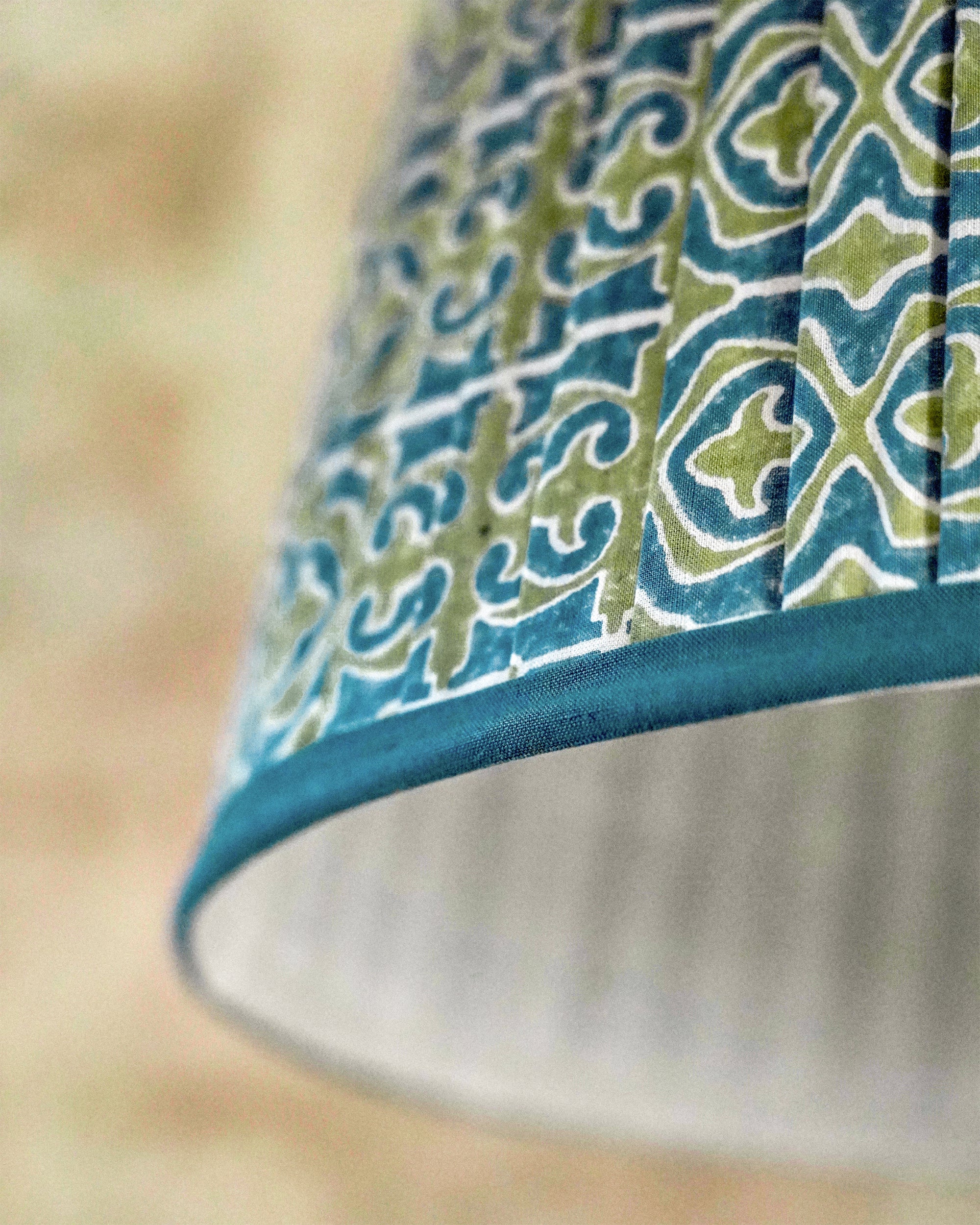 Close-up of a lampshade with a blue and green pattern on a blurred background