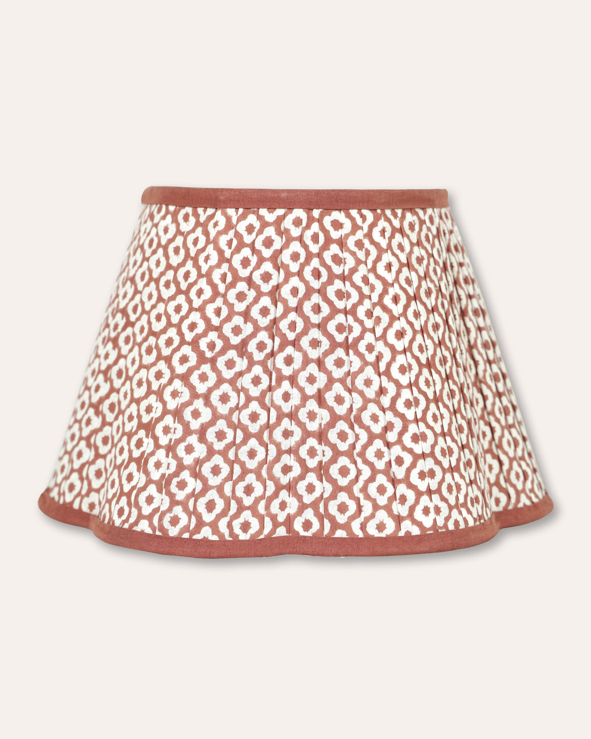 A pleated fabric lampshade with a repeating white floral pattern on a dusty rose background, finished with a solid dusty rose trim.