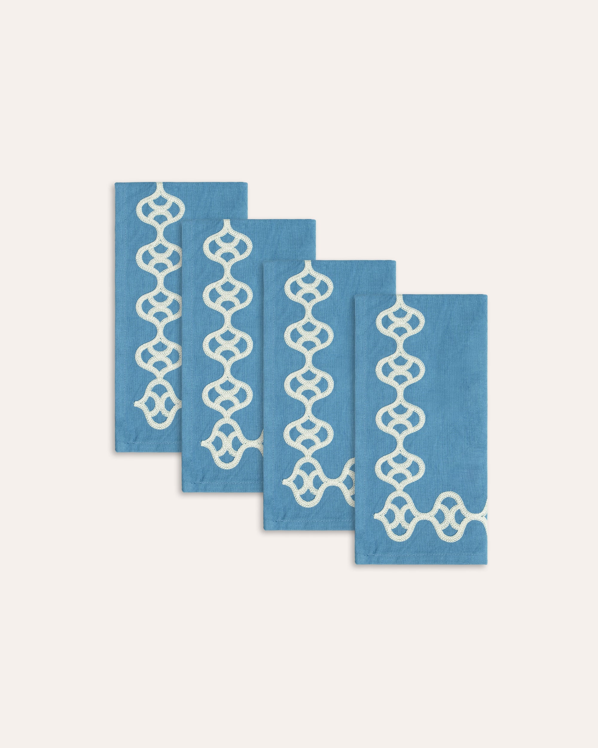 Set of four blue placemats with white geometric patterns on a white background
