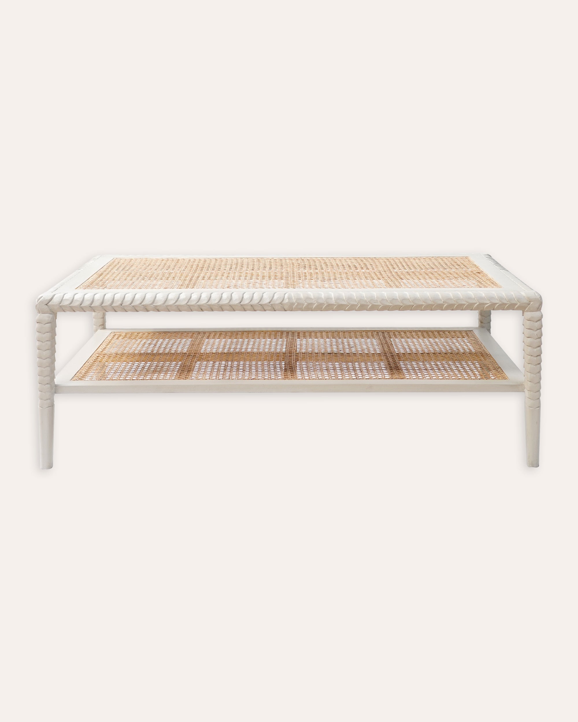A taupe-colored coffee table with hand-carved leaf motifs on the edges and a natural cane interior, featuring a shelf below for extra storage.