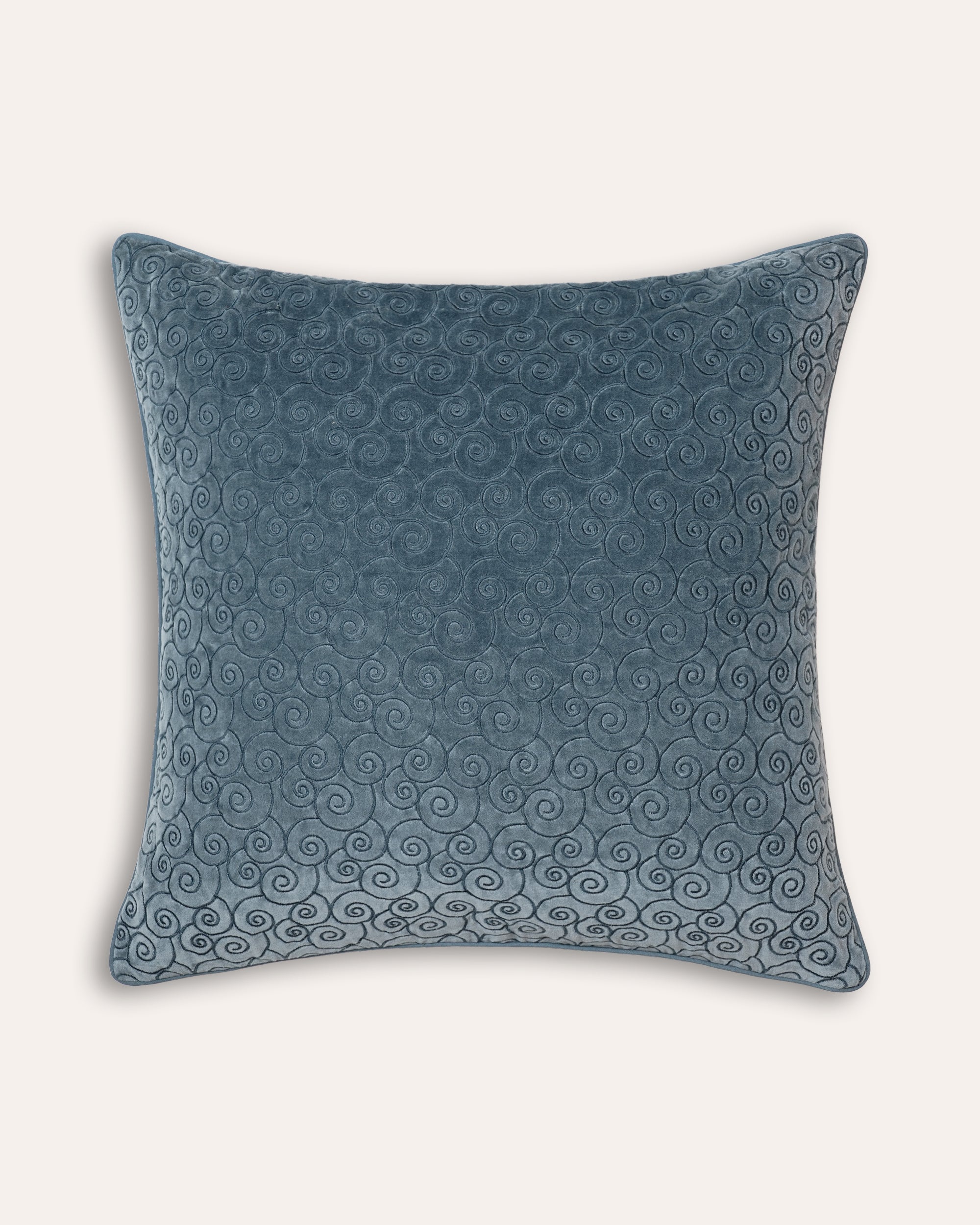 A square-shaped embroidered velvet cushion in blue with a geometric pattern.
