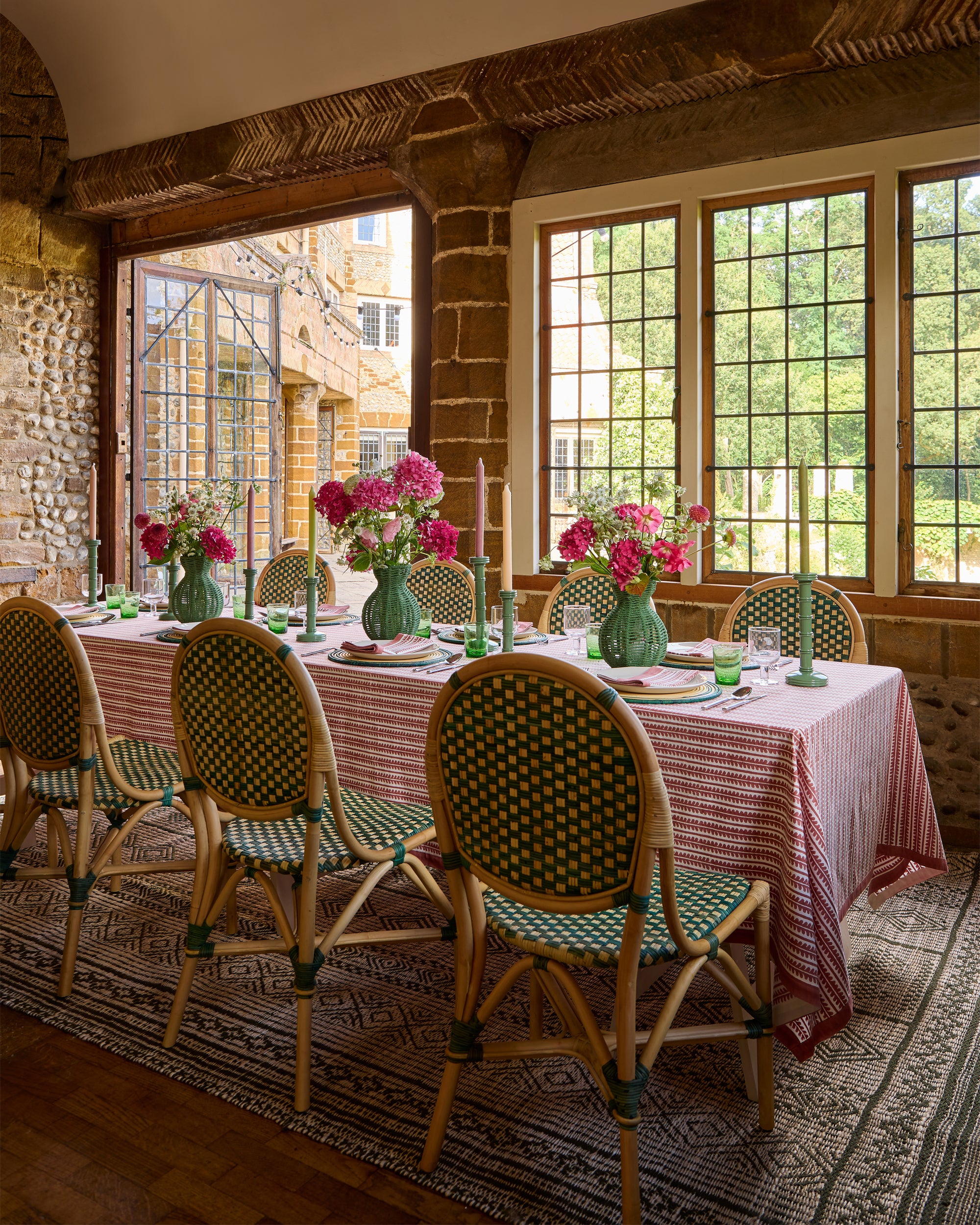 Dining room with a long table set for dinner, chairs, and floral centerpieces.