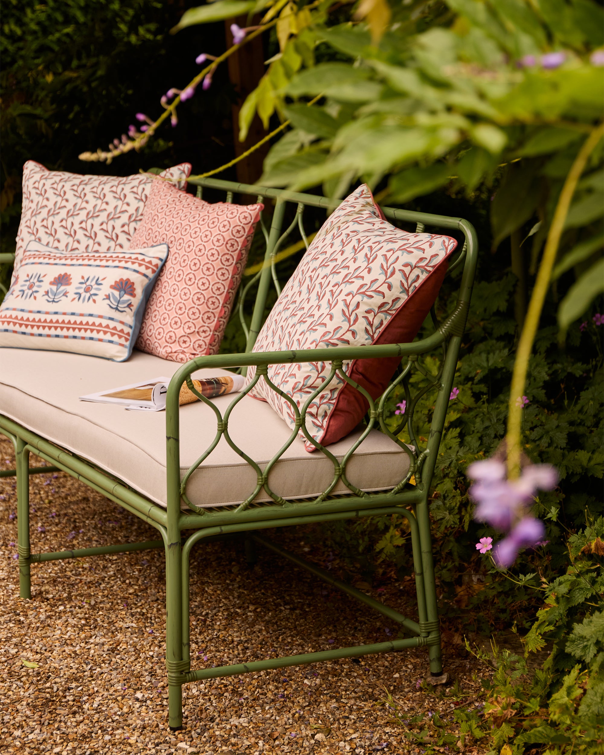 Pretty spring summer outdoor seating lifestyle image, featuring the curato sofa styled with Birdie Fortescue's SS25 pink and blue cushions