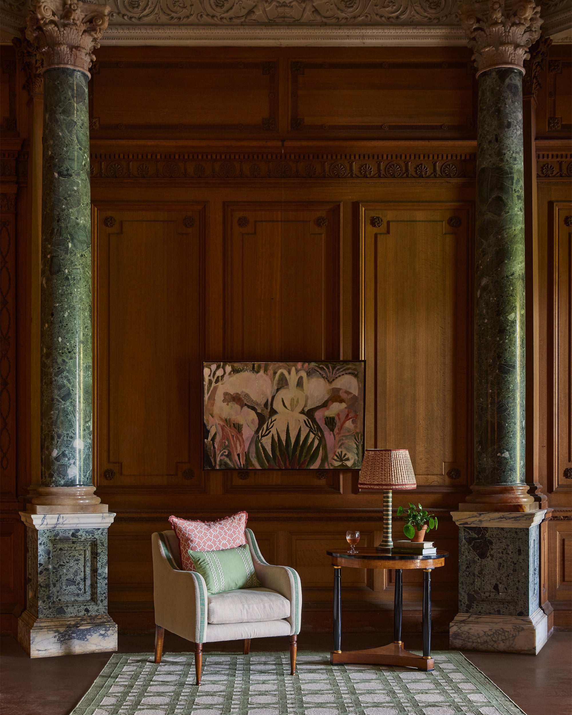 Decorative interior with a chair, table, and artwork on a wooden paneled wall.