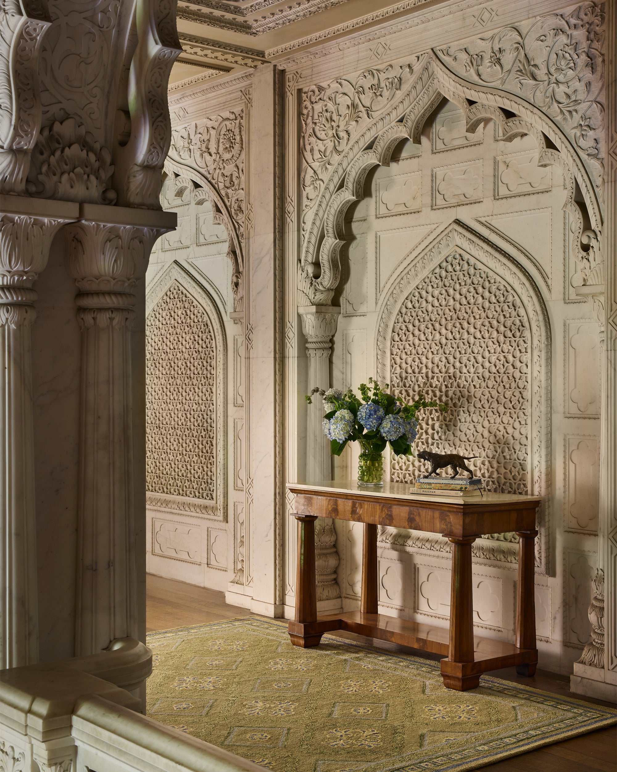 Decorative interior with intricate wall carvings and a wooden table with flowers.