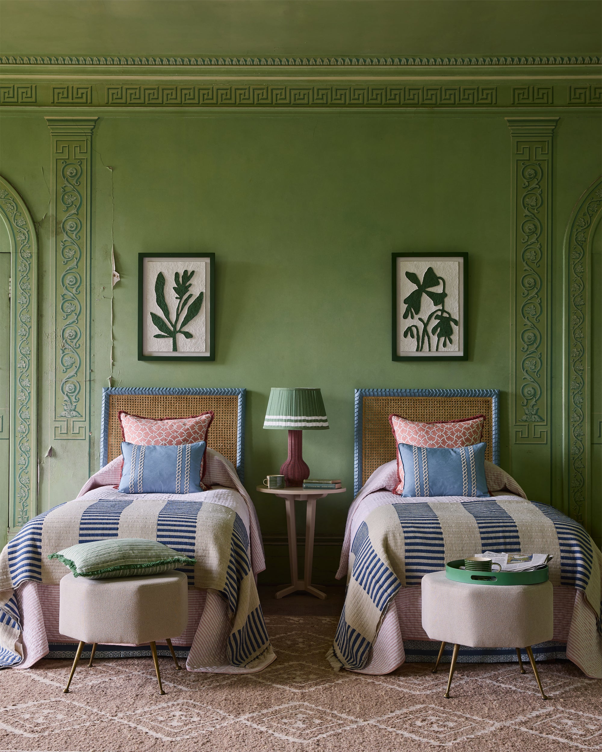 Two twin beds with striped bedding in a room with green walls and decorative molding.