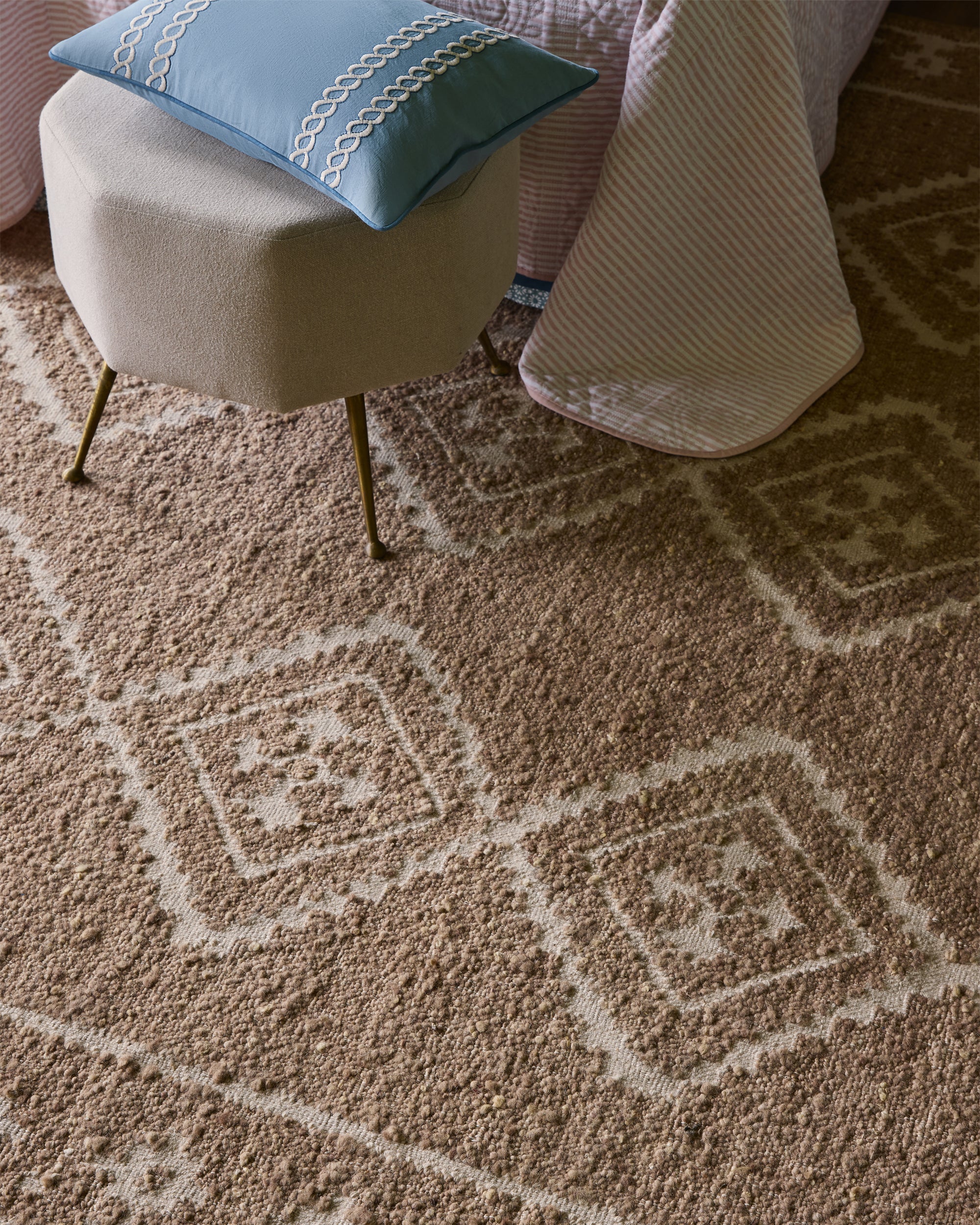 Patterned rug with a blue pillow on a chair in the corner