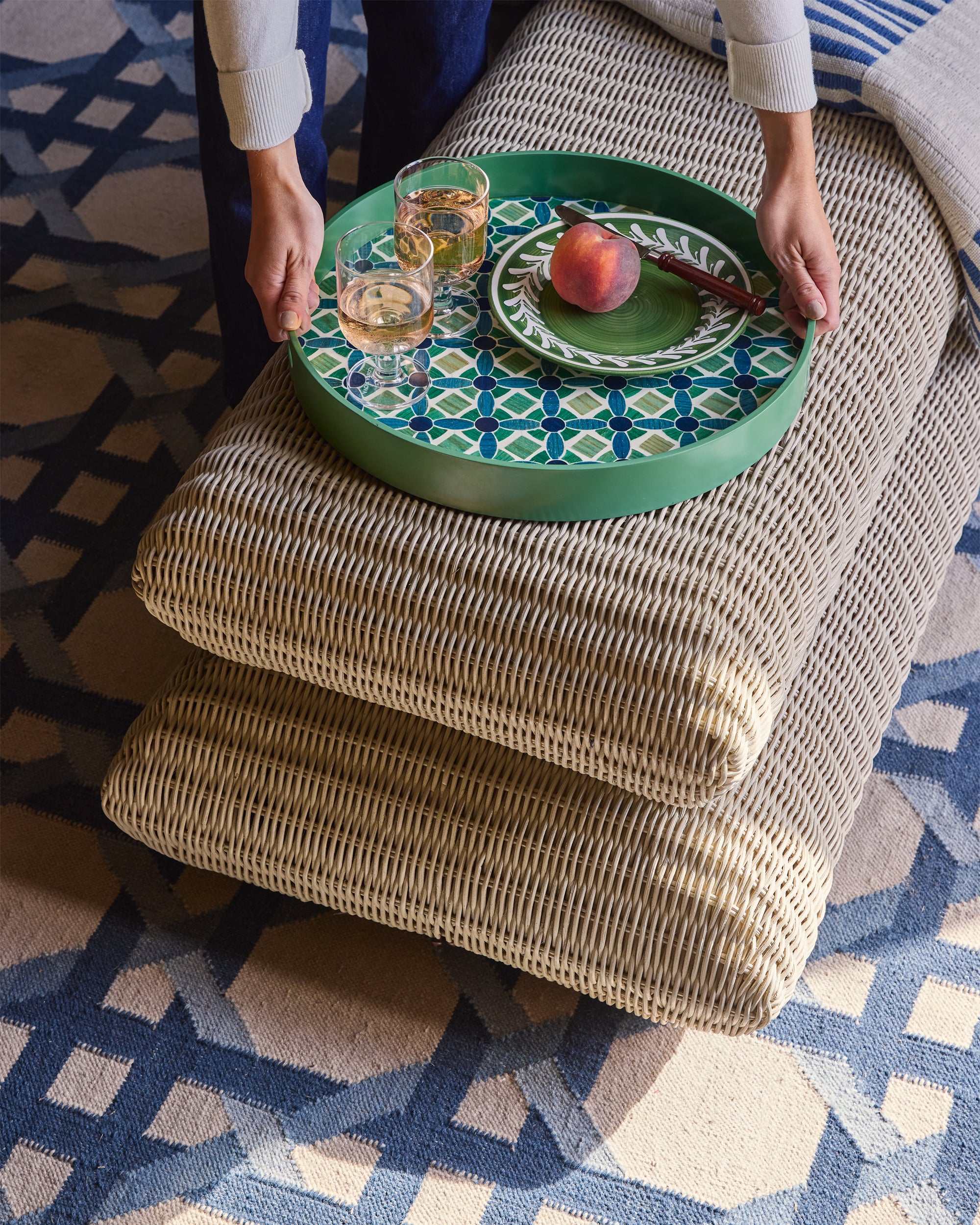 Person holding a green tray with a pattern on a textured surface