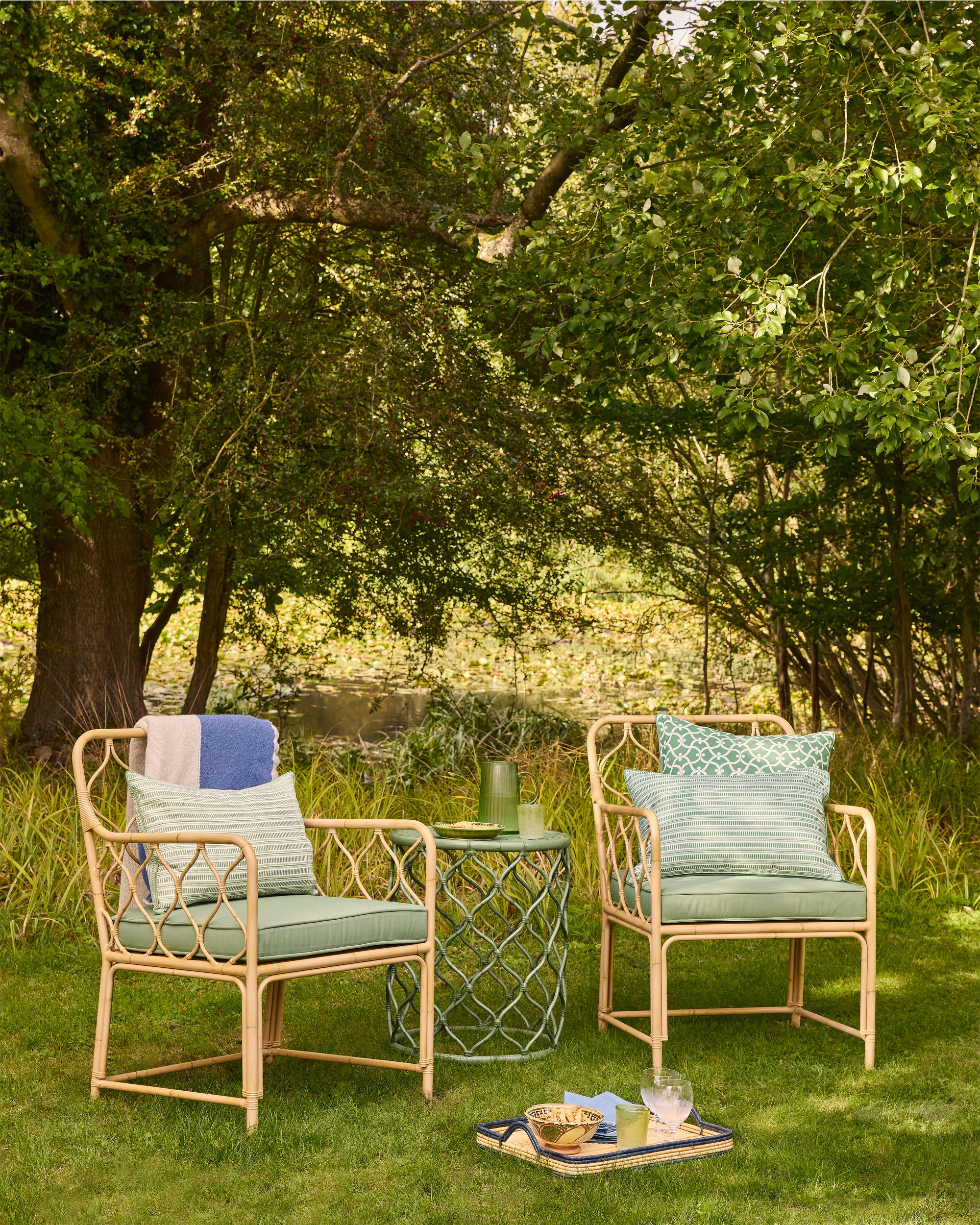 Outdoor furniture set with two chairs and a table in a garden setting.