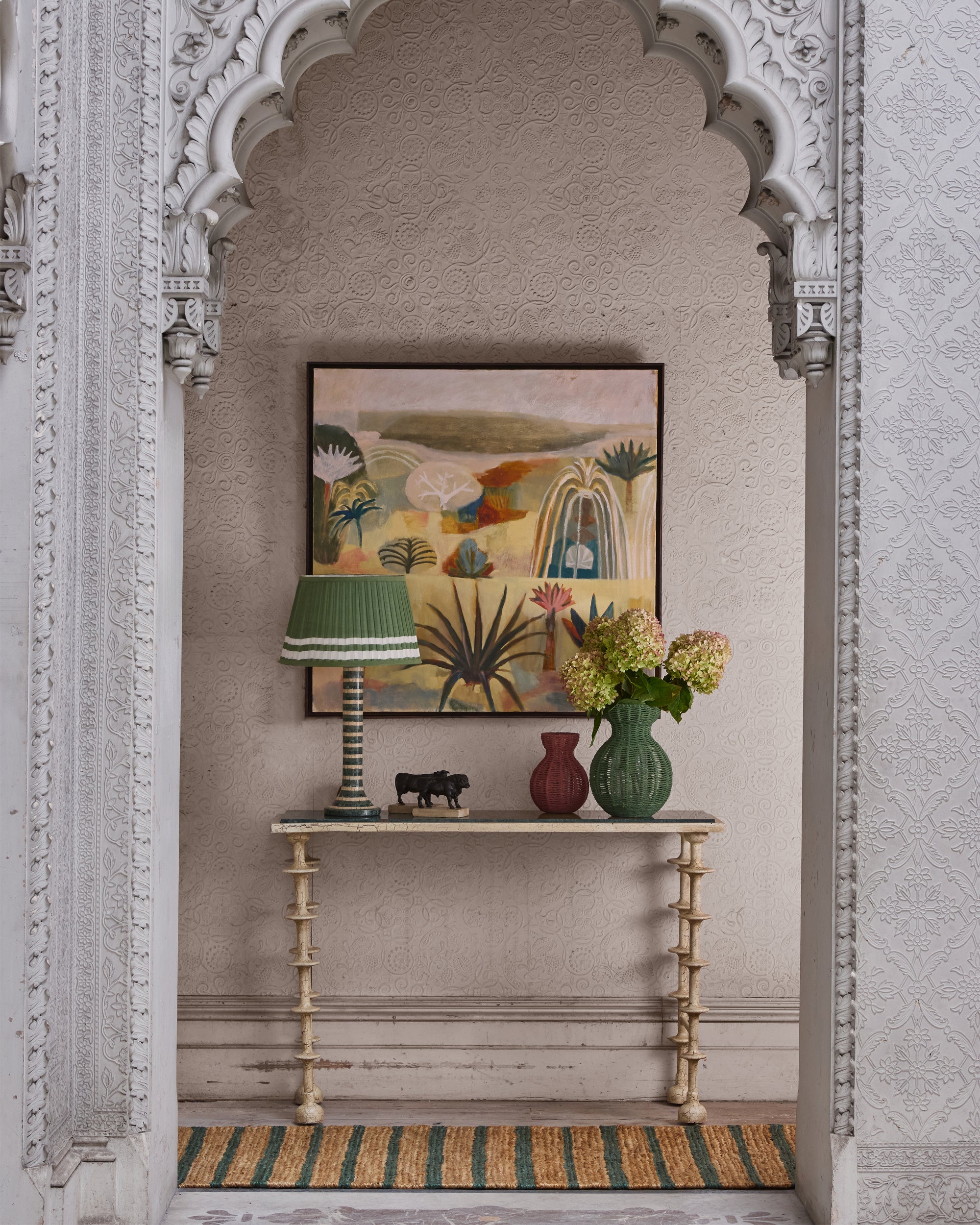 Decorative interior with a table, lamp, vases, and artwork on a wall.