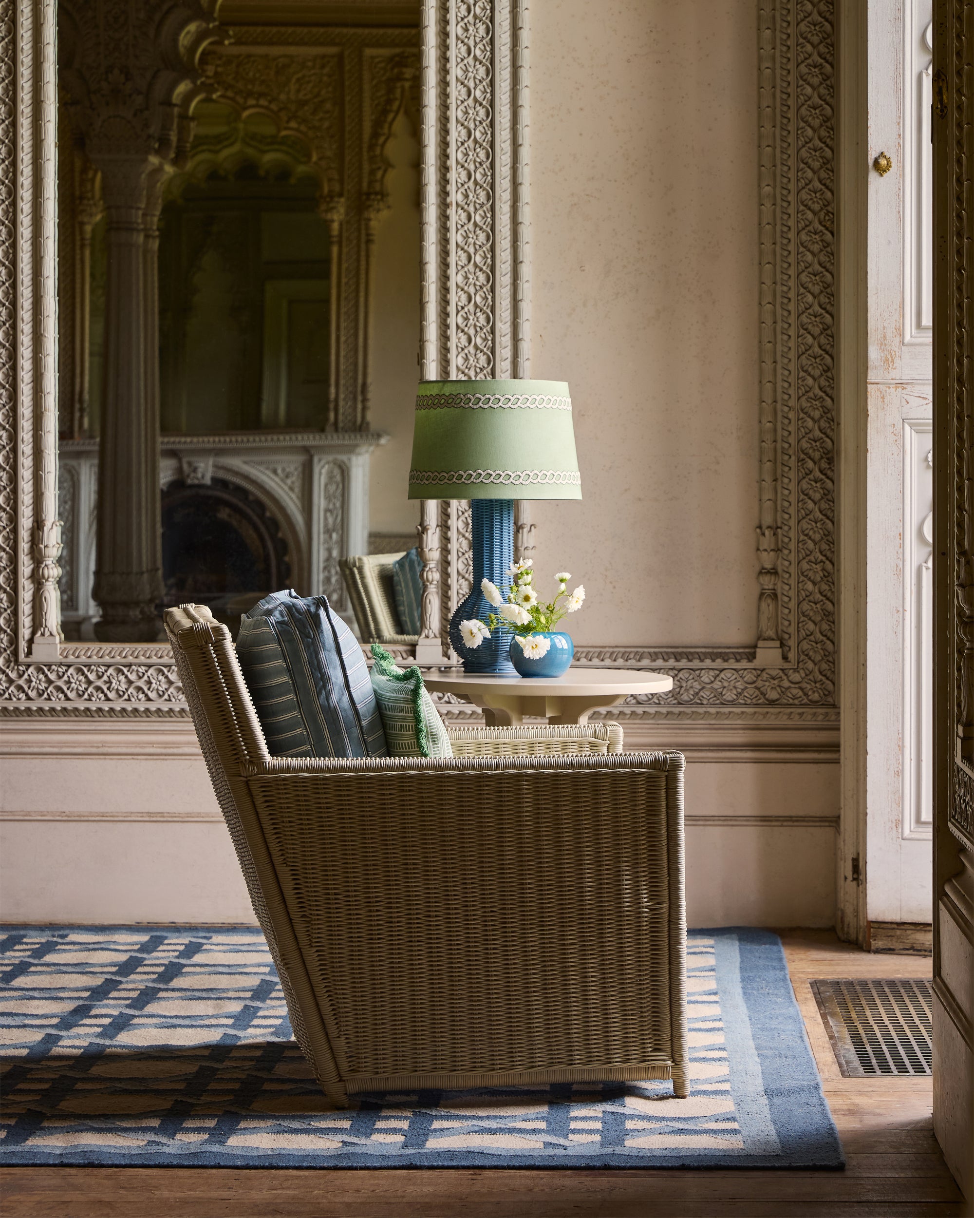 Wicker chair in a room with ornate wall decorations and a lamp.