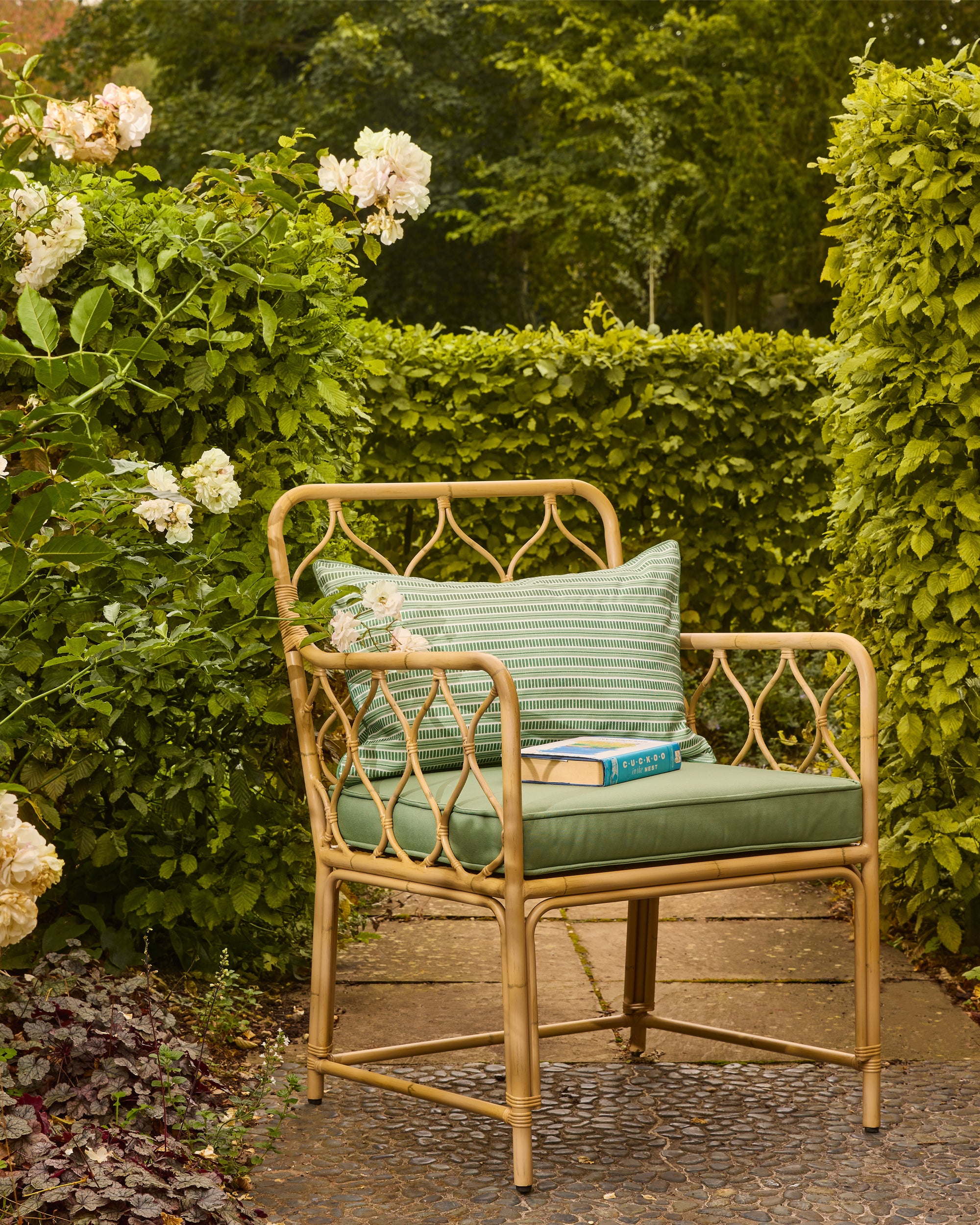 Bamboo style chair with green cushions in a garden setting