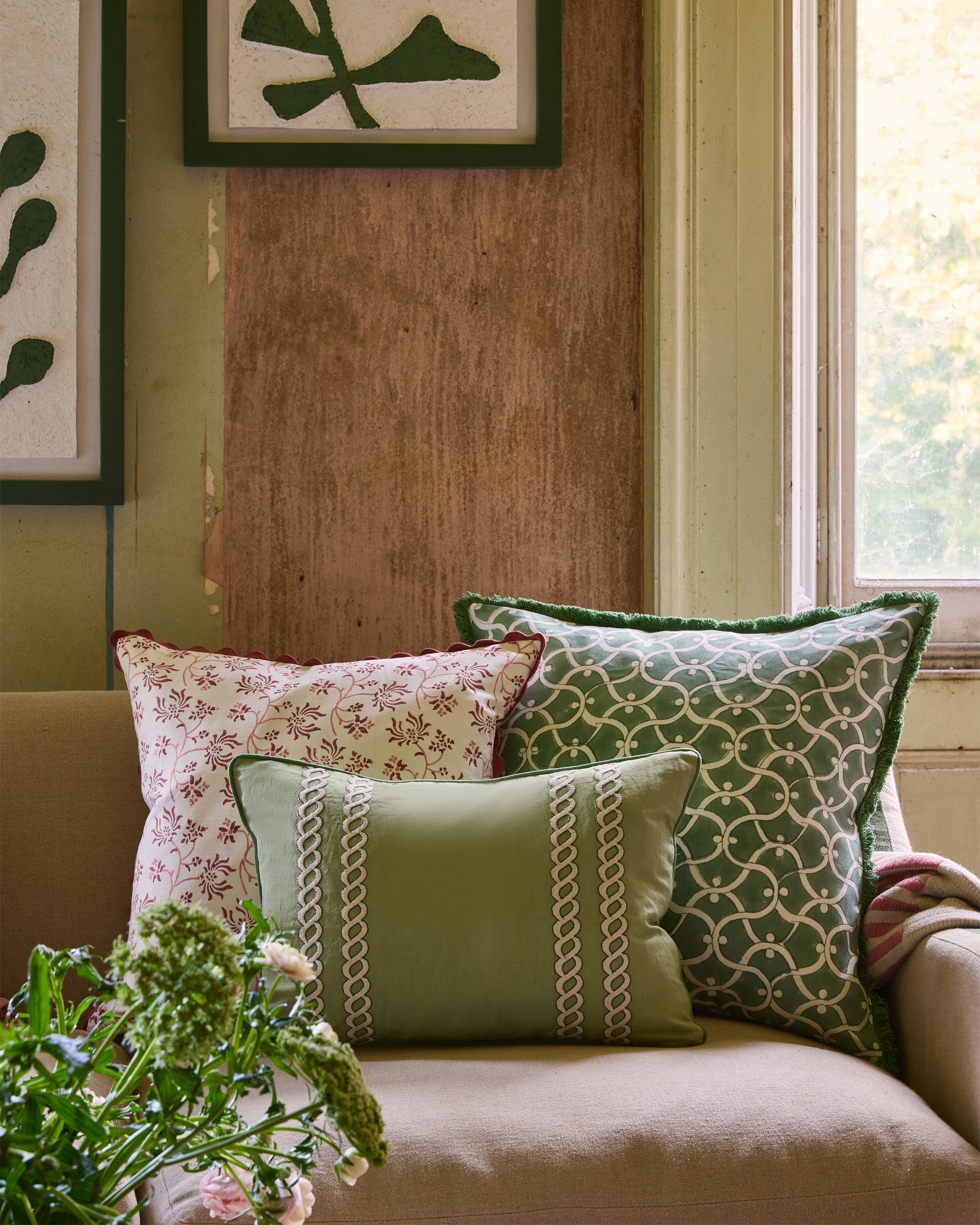Decorative pillows on a sofa with a window and plant in the background