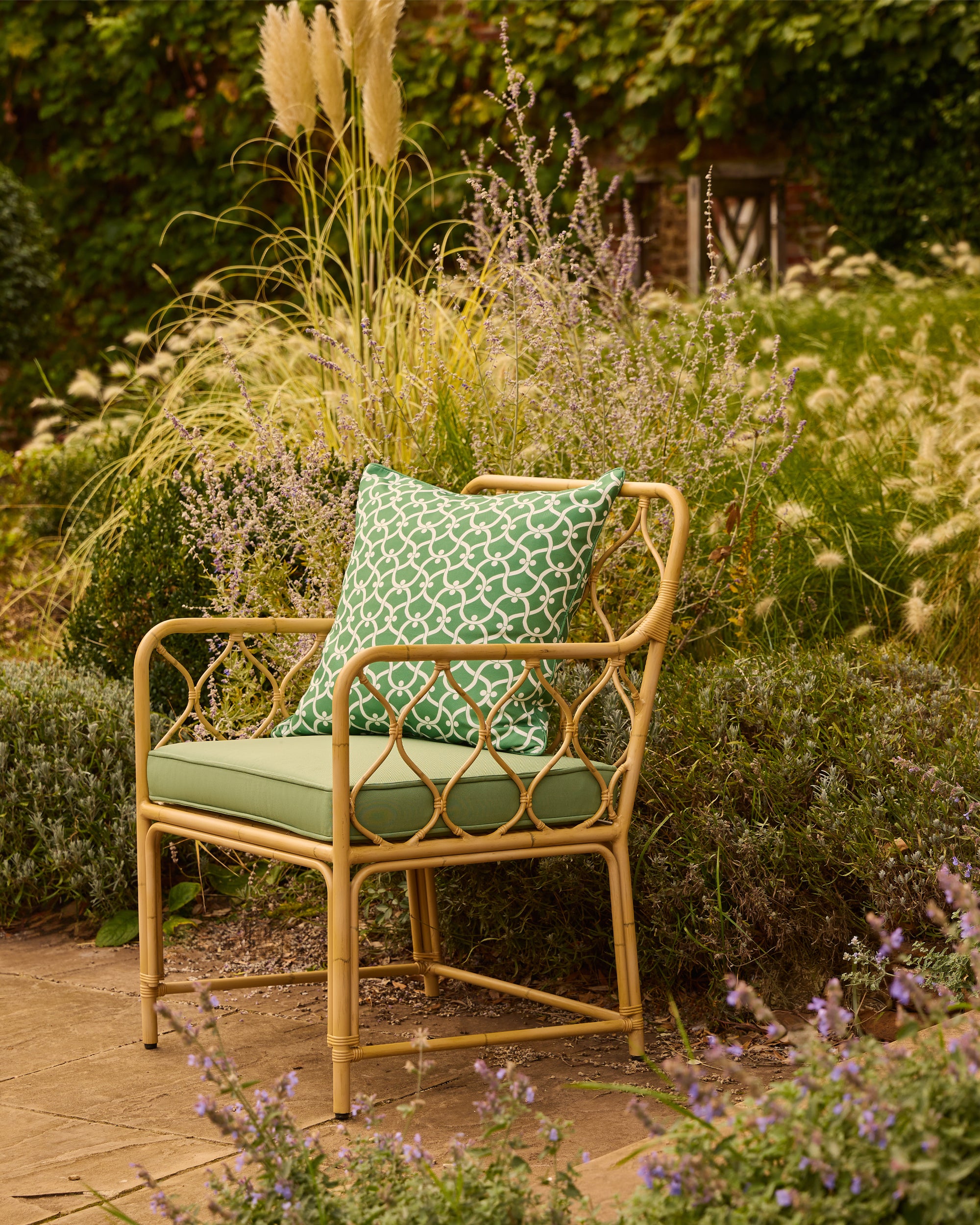 Aluminium chair with a green cushion and patterned pillow in a garden setting