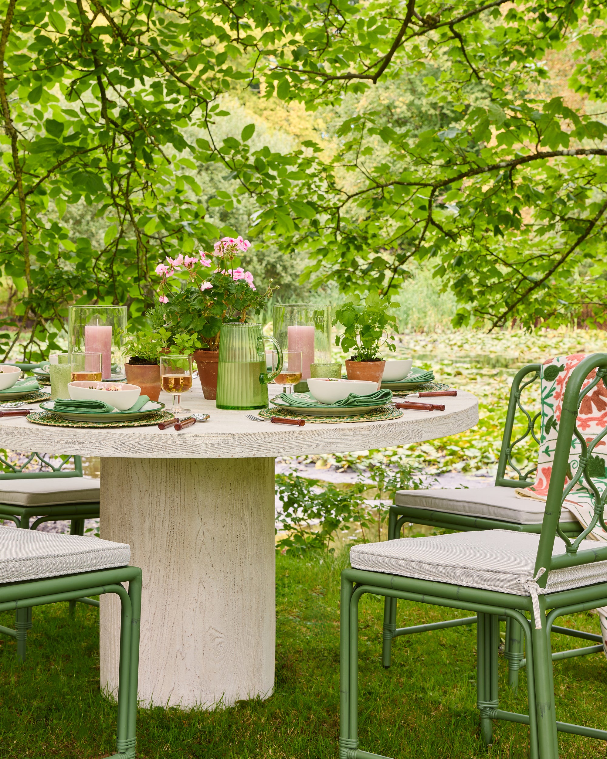 Outdoor dining setup with a table, chairs, and decorative elements in a garden setting.