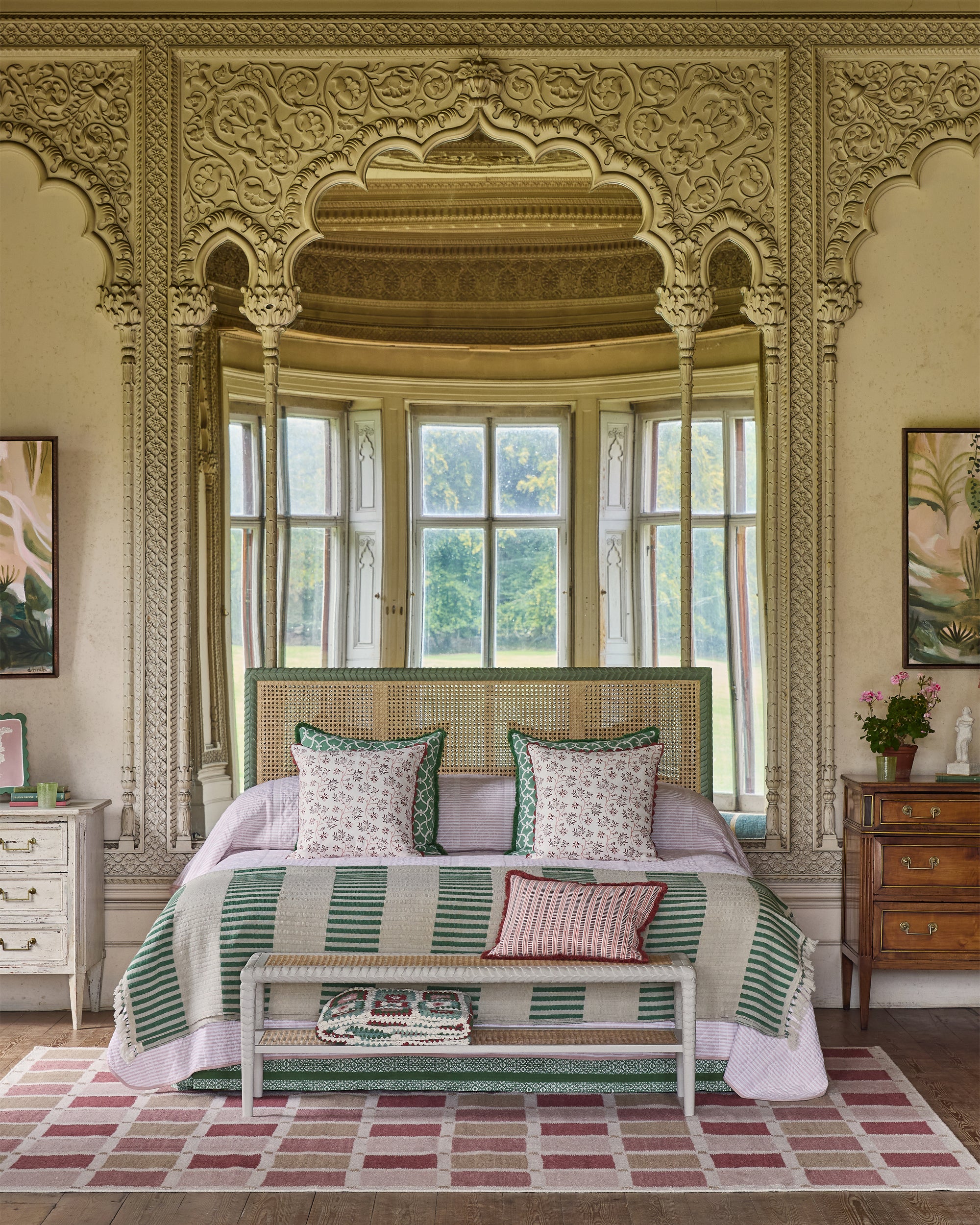 Decorative bedroom with ornate wall designs and a bed with striped bedding.