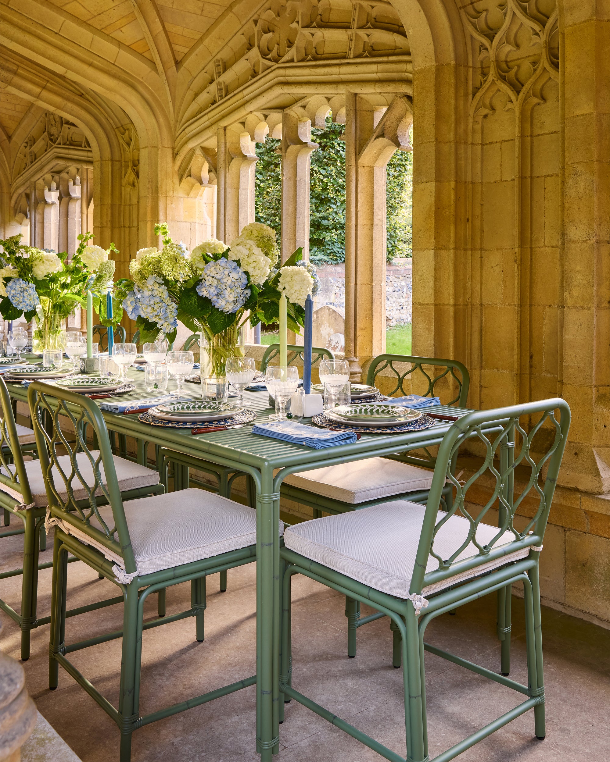 Outdoor dining setup with green chairs and tables in a historic building setting.
