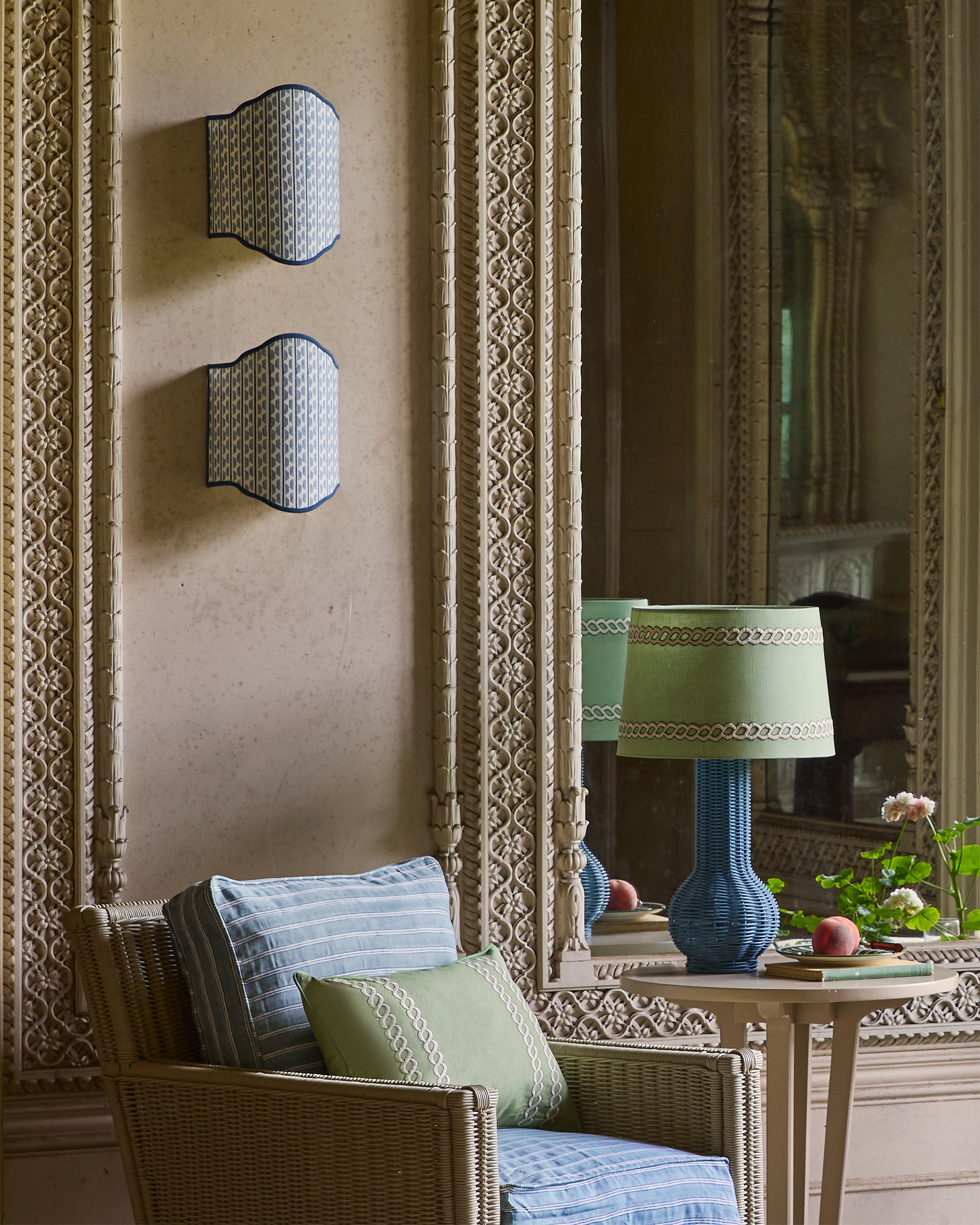 Decorative interior with wicker chair, patterned wall, and ornate mirror.