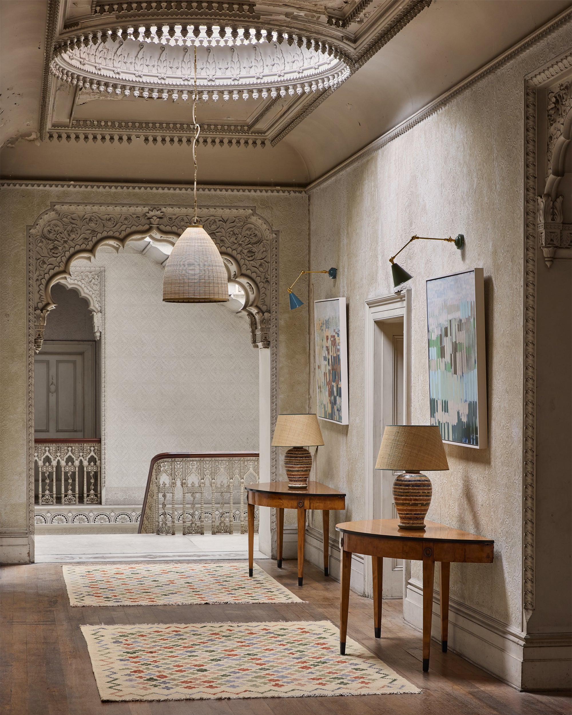 Elegant interior hallway with decorative lighting, tables, and artwork.