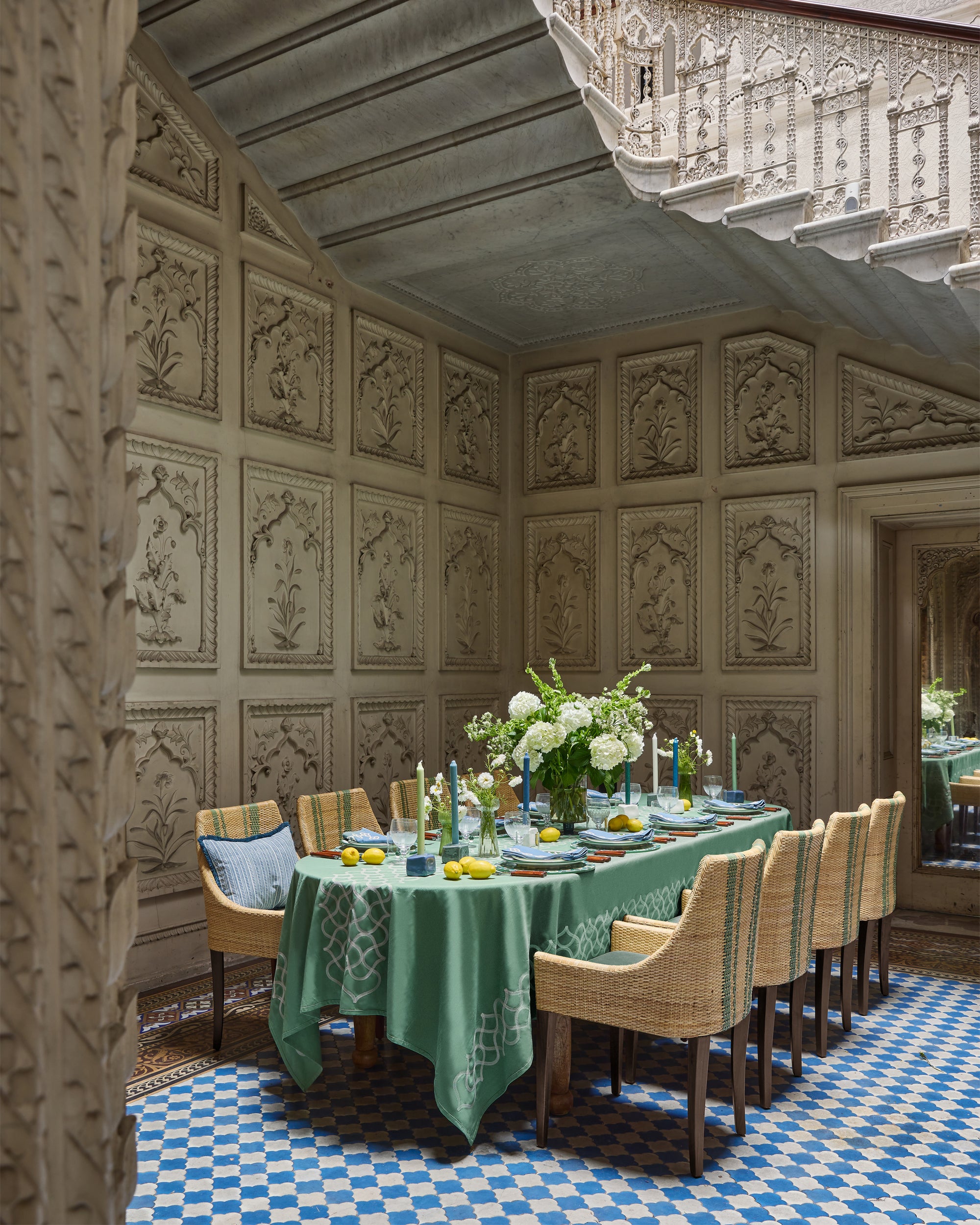 Dining room with ornate walls, checkered floor, and a table set for dinner.