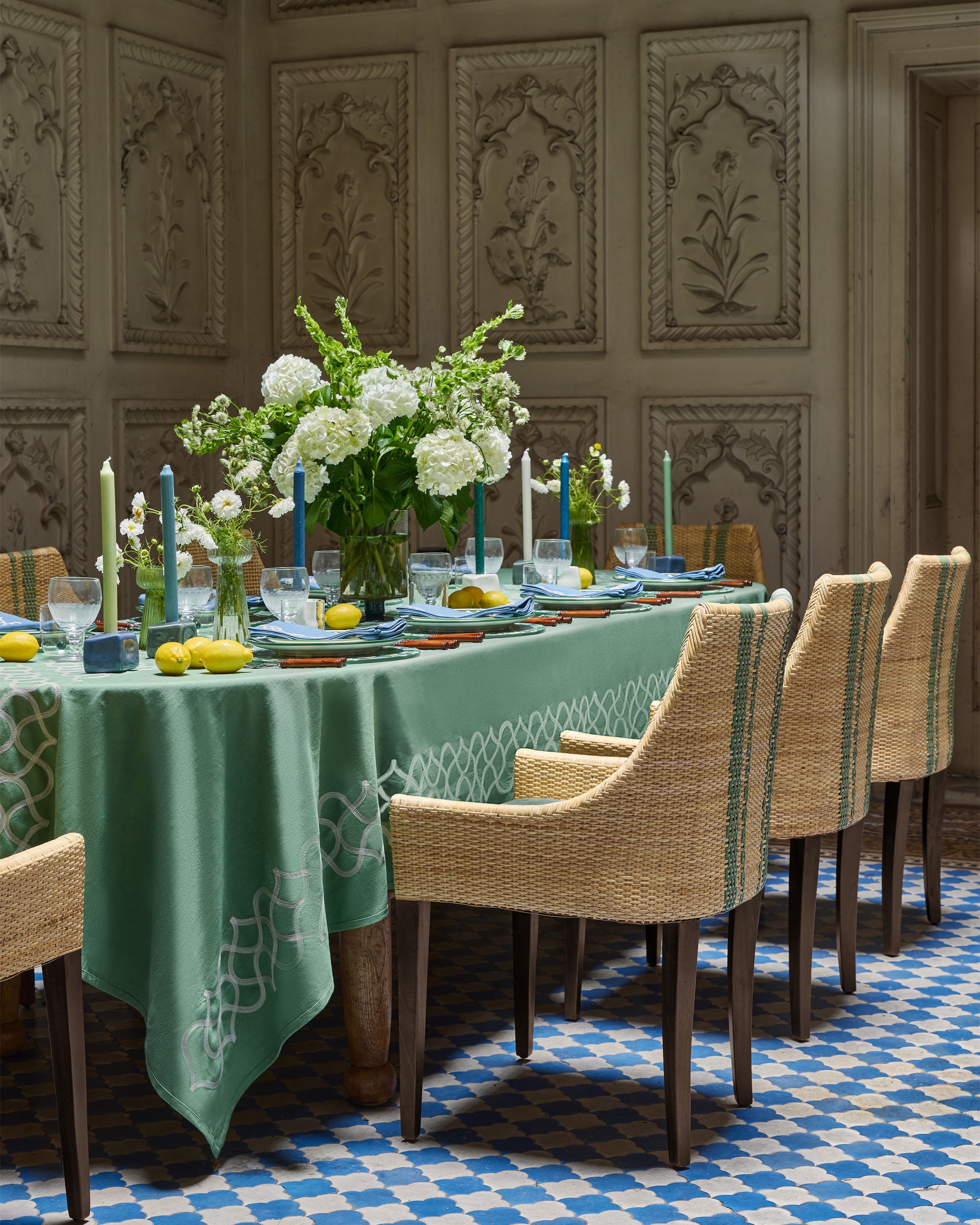 Dining room with a long table set for a meal, featuring a green tablecloth and decorative elements.
