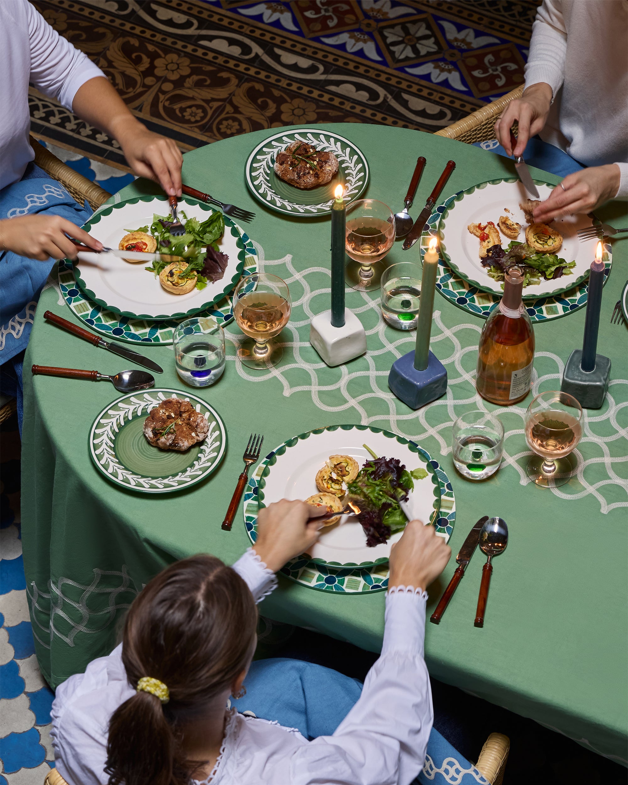 People enjoying a meal together at a decorated table with plates, cutlery, and drinks.