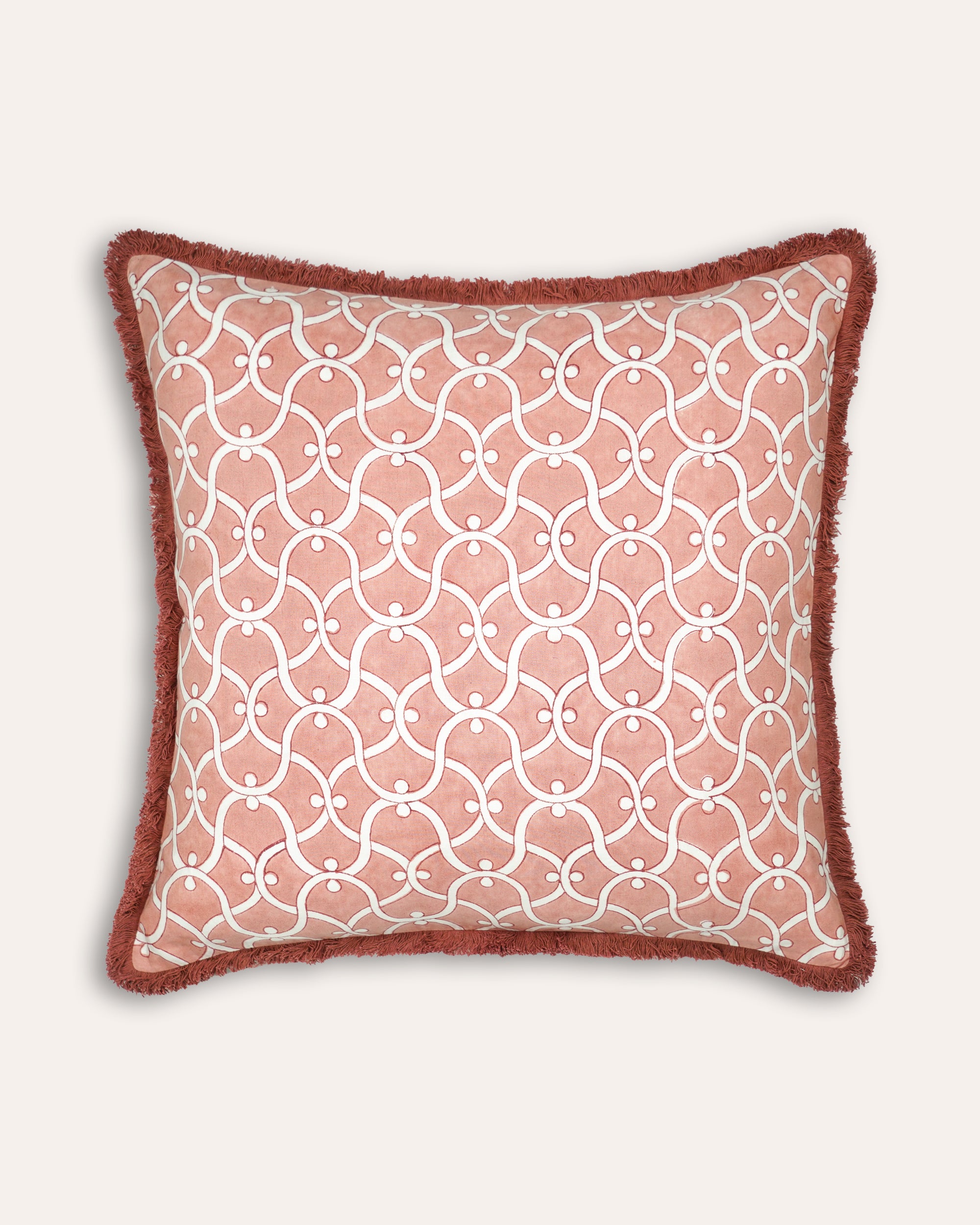 Decorative block printed pink and red square cushion with geometric pattern on a plain background