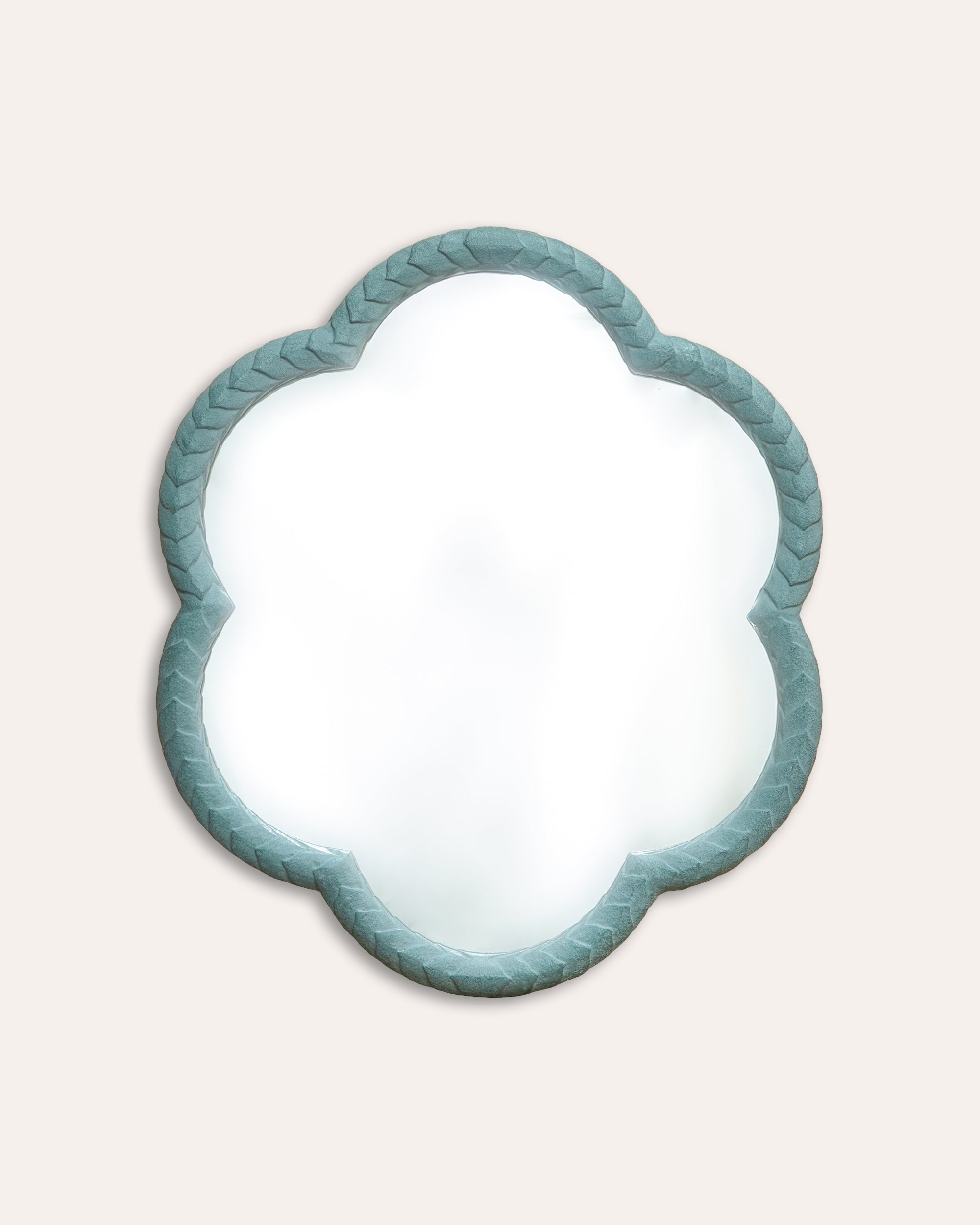 Decorative mirror with a scalloped edge and teal frame on a light beige background
