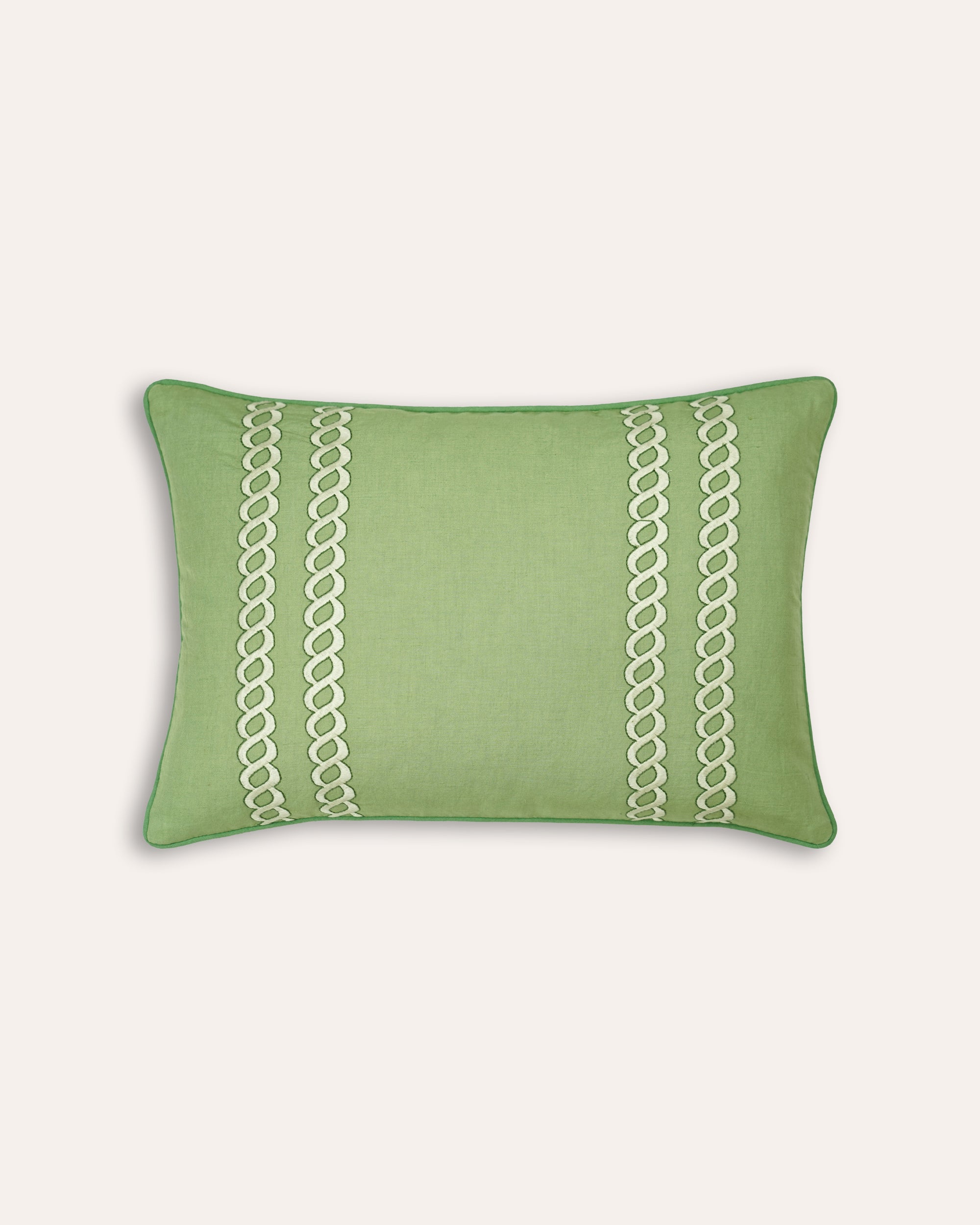 Green cushion with white lace pattern on a light grey background