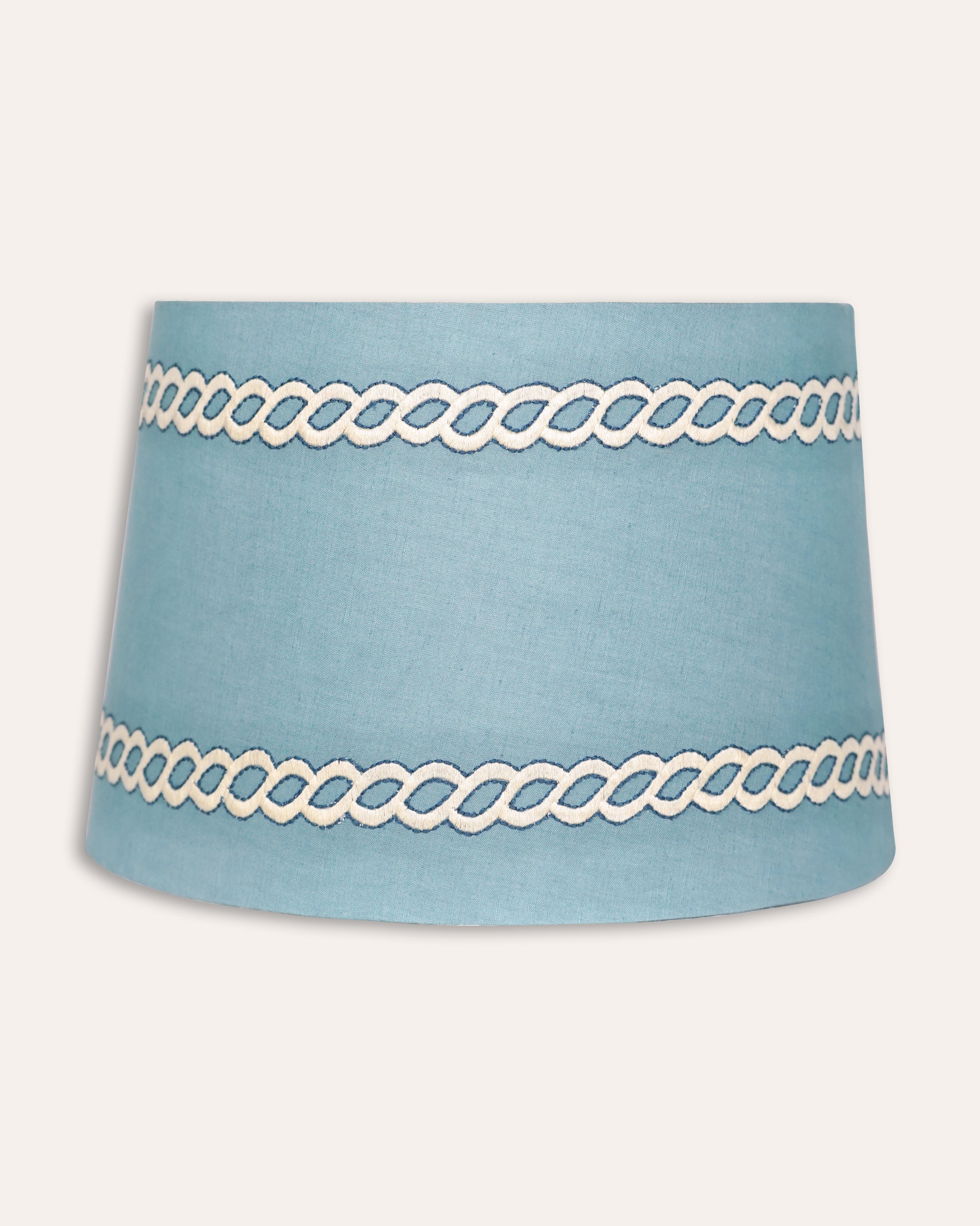 Blue lampshade with white decorative banding on a white background