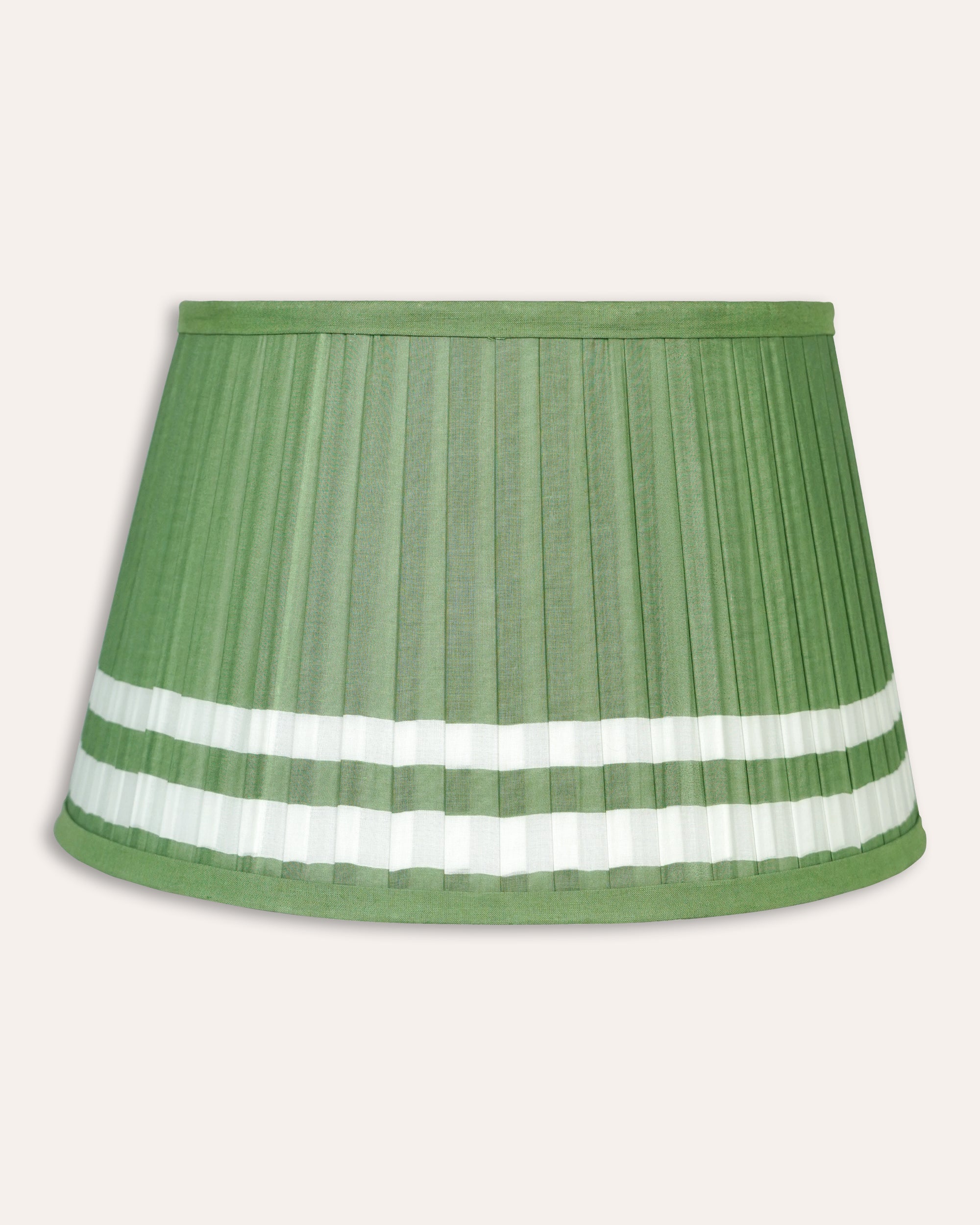 Green pleated lampshade with white trim on a beige background