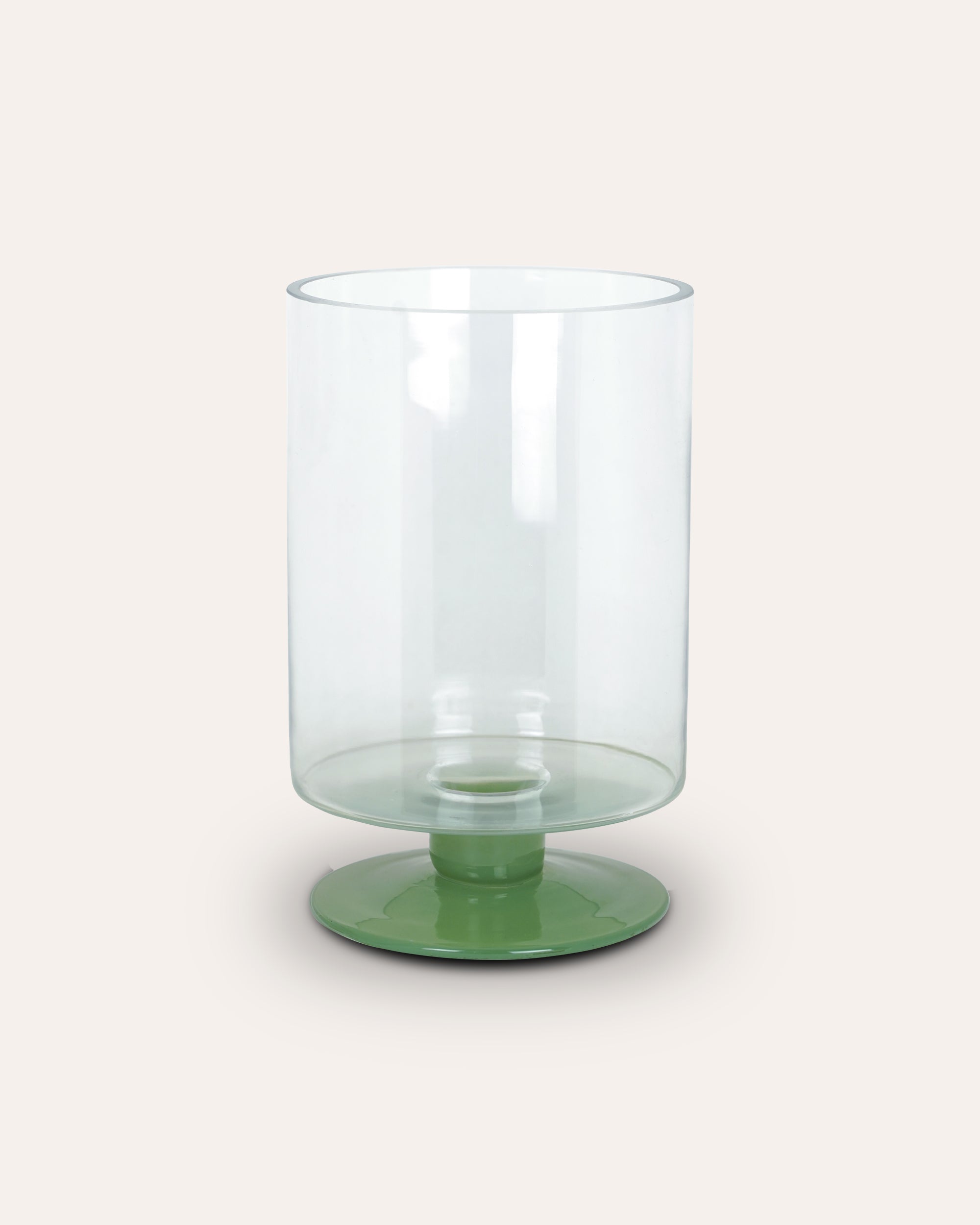 Clear glass candle holder with a green base on a white background