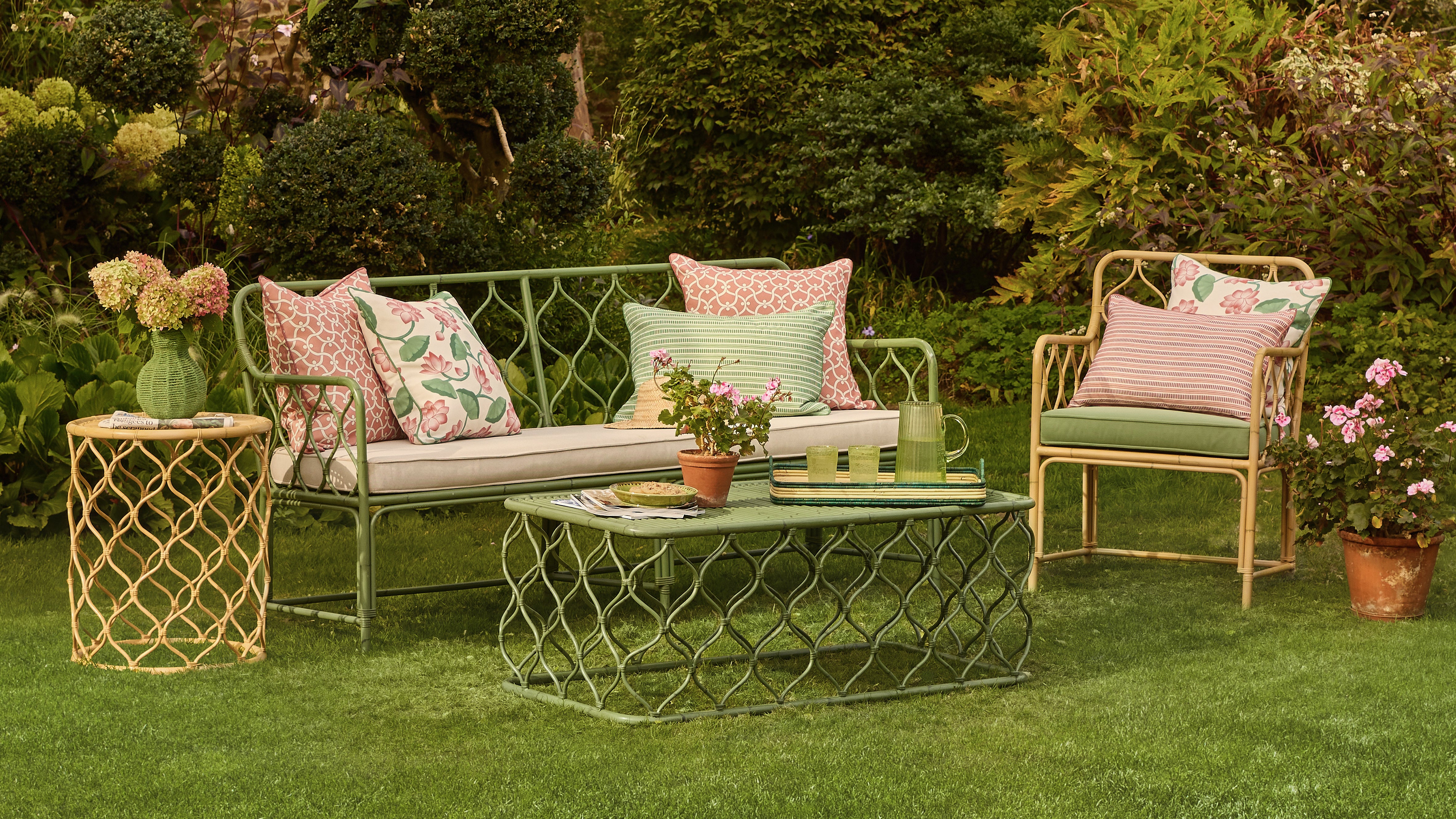 Outdoor garden setting with patio furniture including a sofa, chairs, and coffee table.