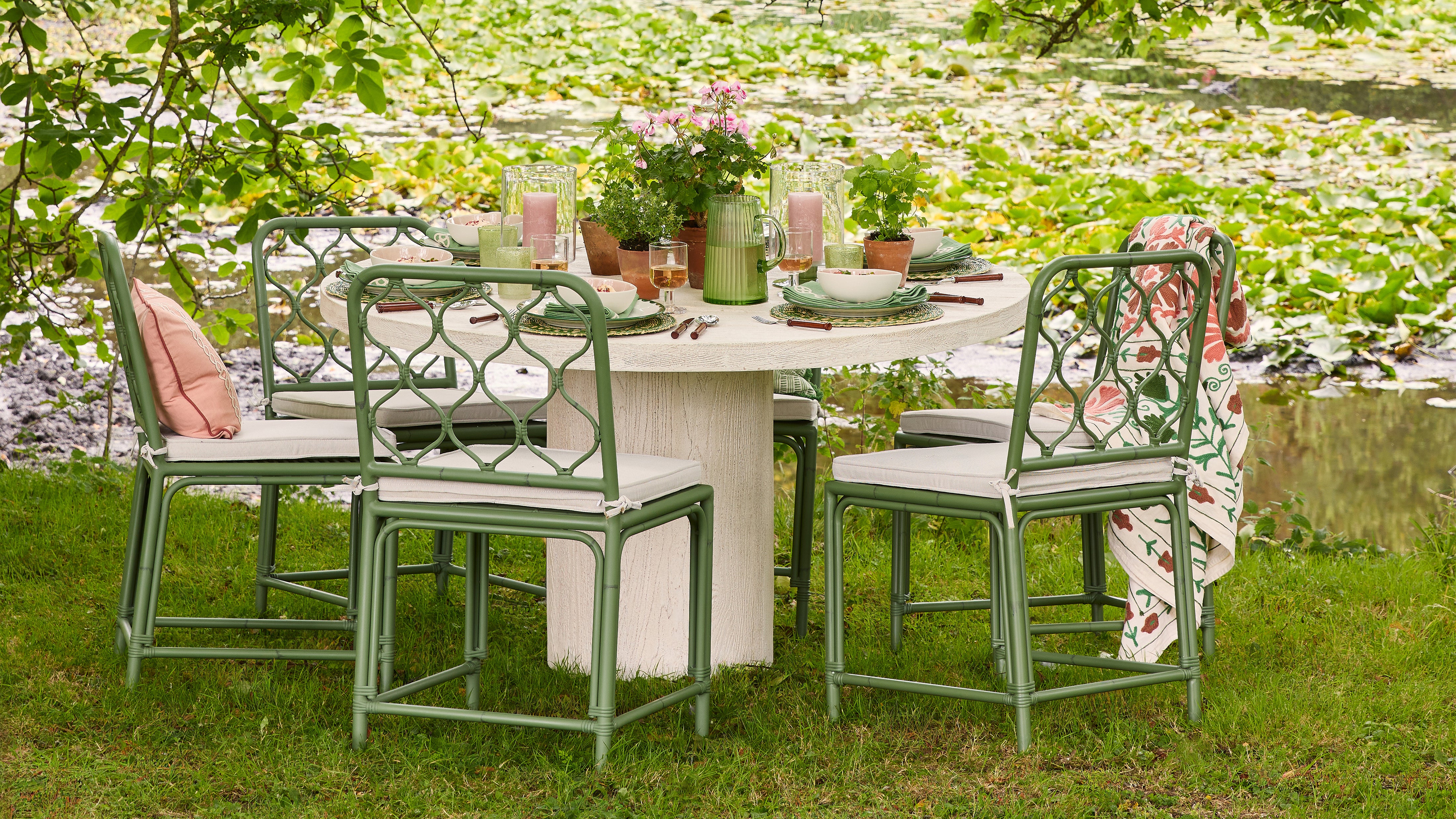 Outdoor dining setup with green chairs and a table by a pond