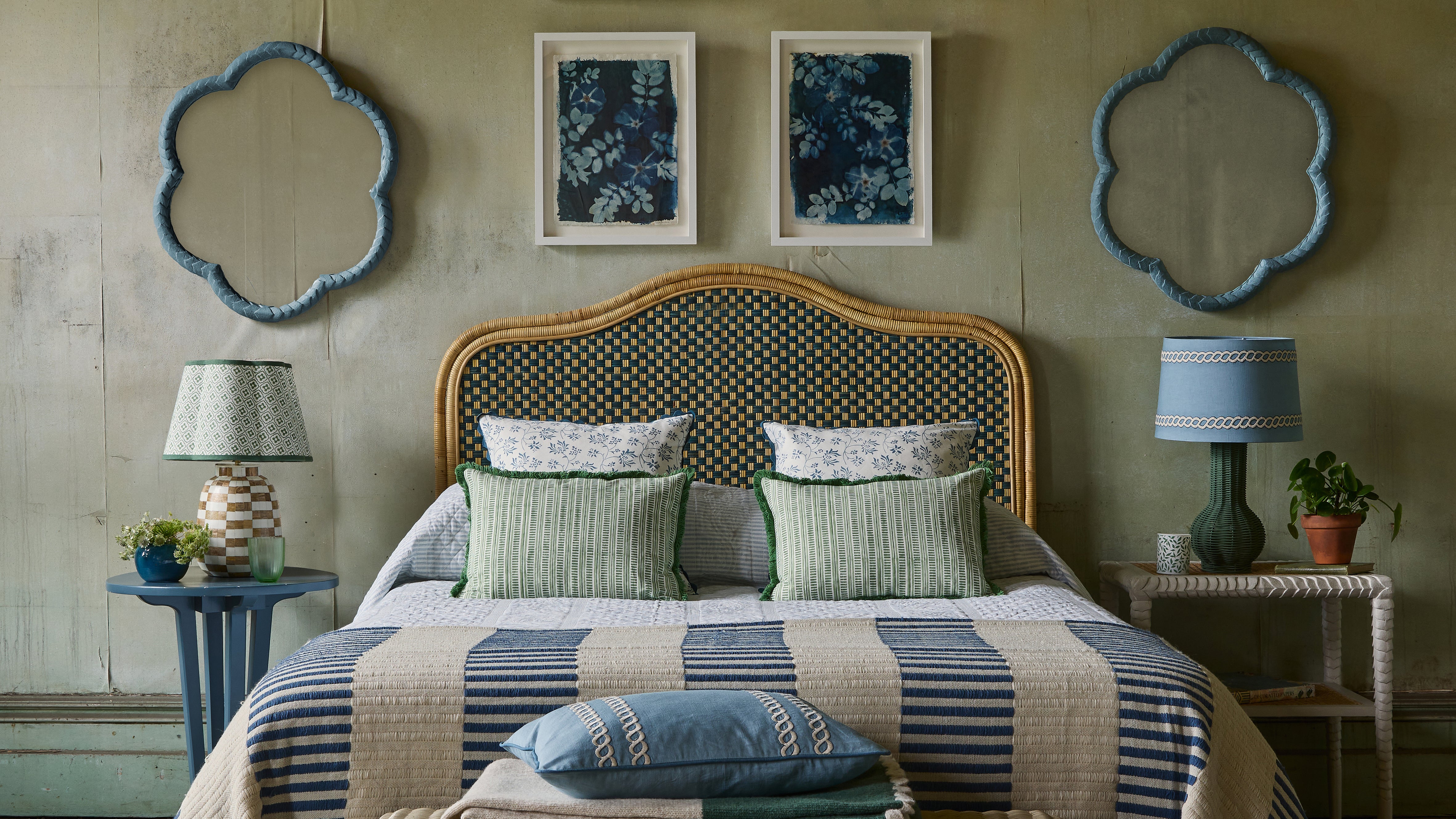Bedroom with a bed, nightstands, lamps, and decorative mirrors on a green wall.