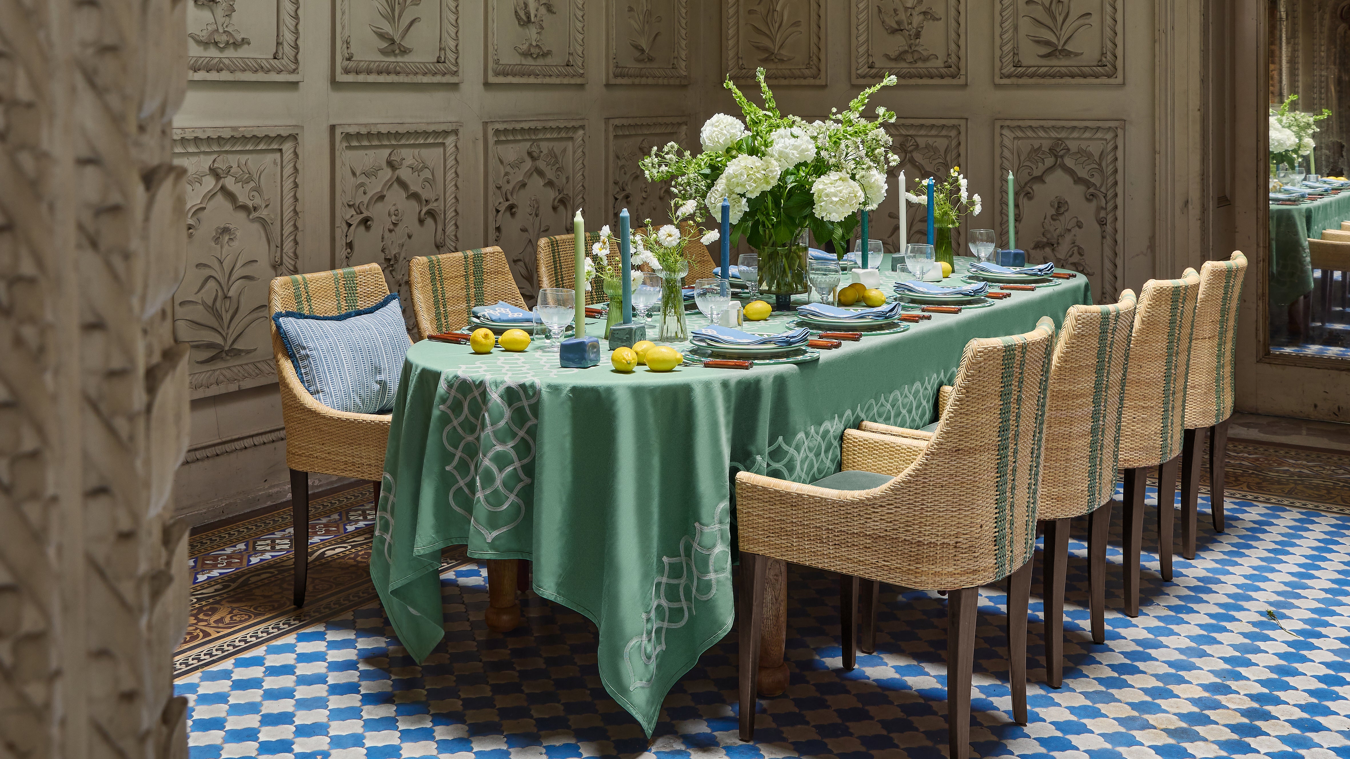 Dining room with a long table set for a meal, featuring a green tablecloth and decorative items.