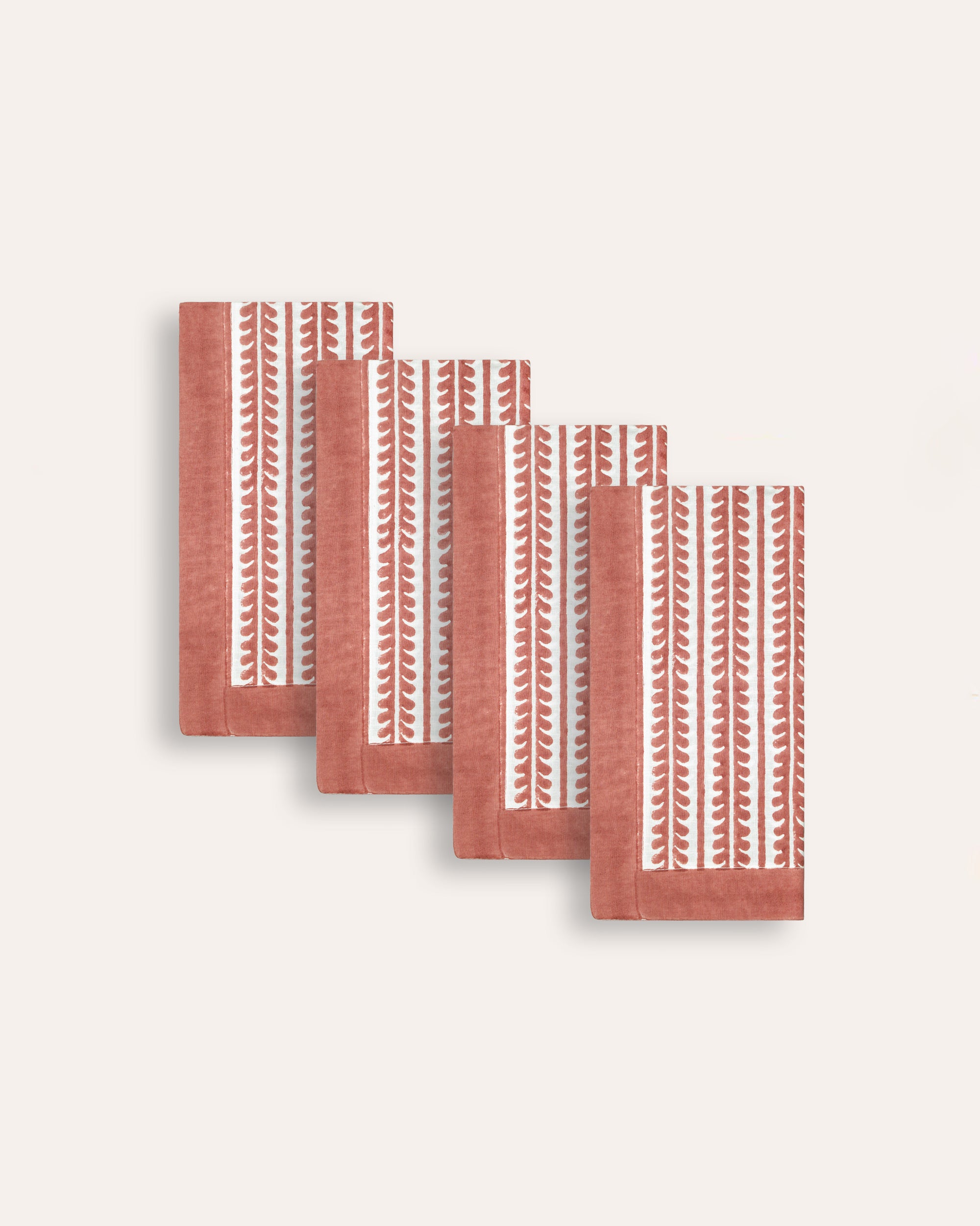 Set of four red bel patterned napkins with a red border on a taupe background