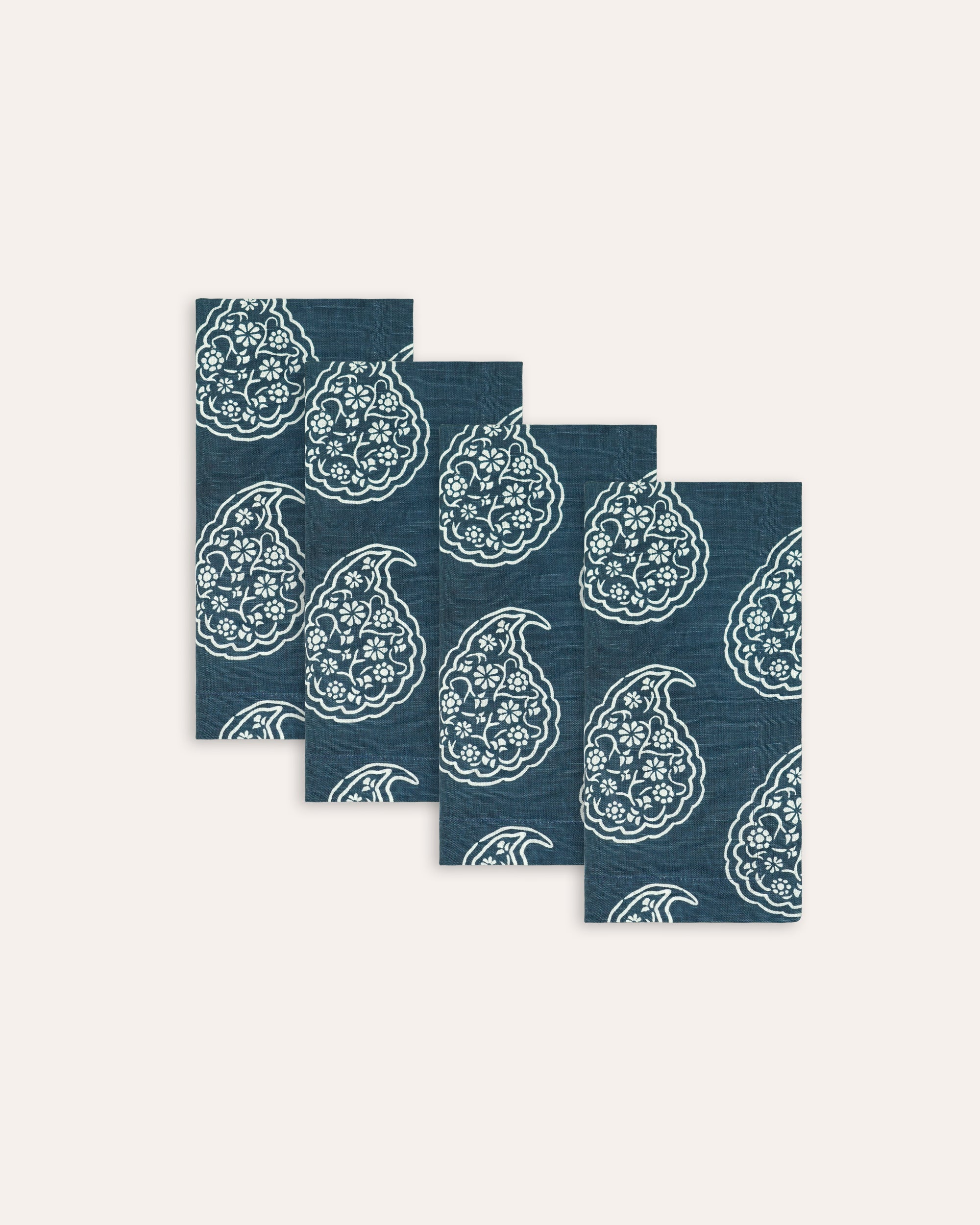 Set of four blue napkins with white paisley patterns on a white background