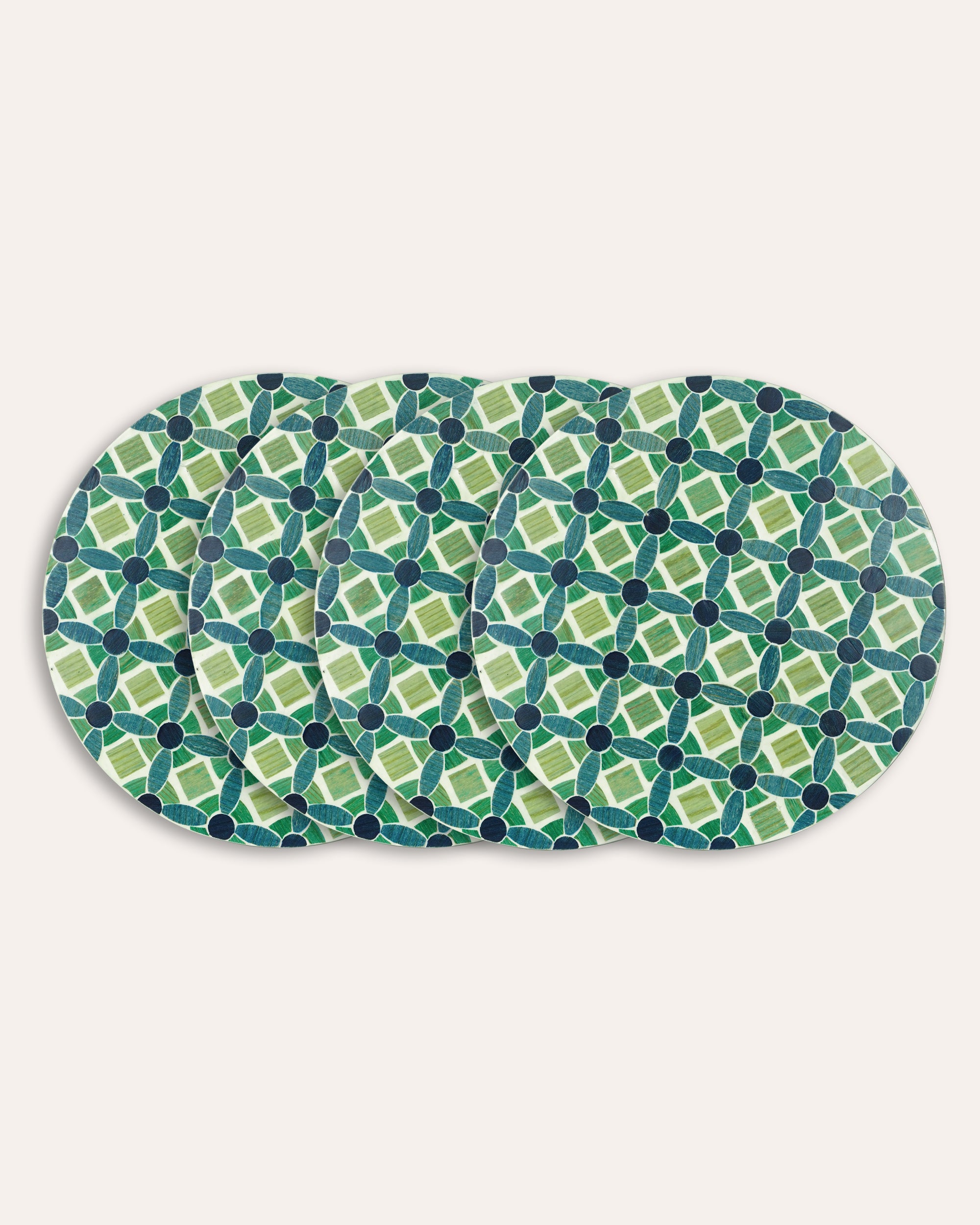 Set of four green and blue patterned placemats on a white background