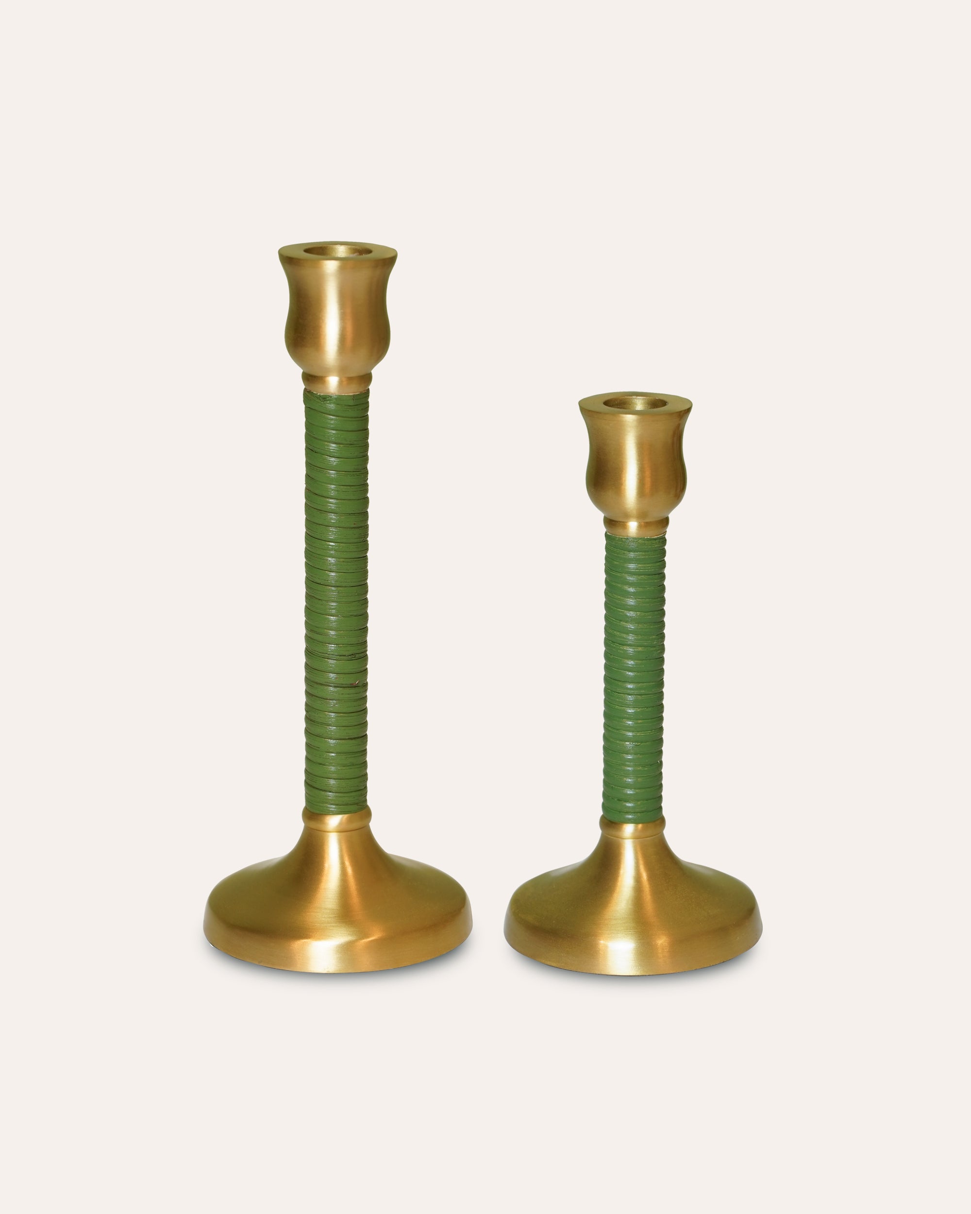 Two brass candle holders with green spiral designs on a beige background