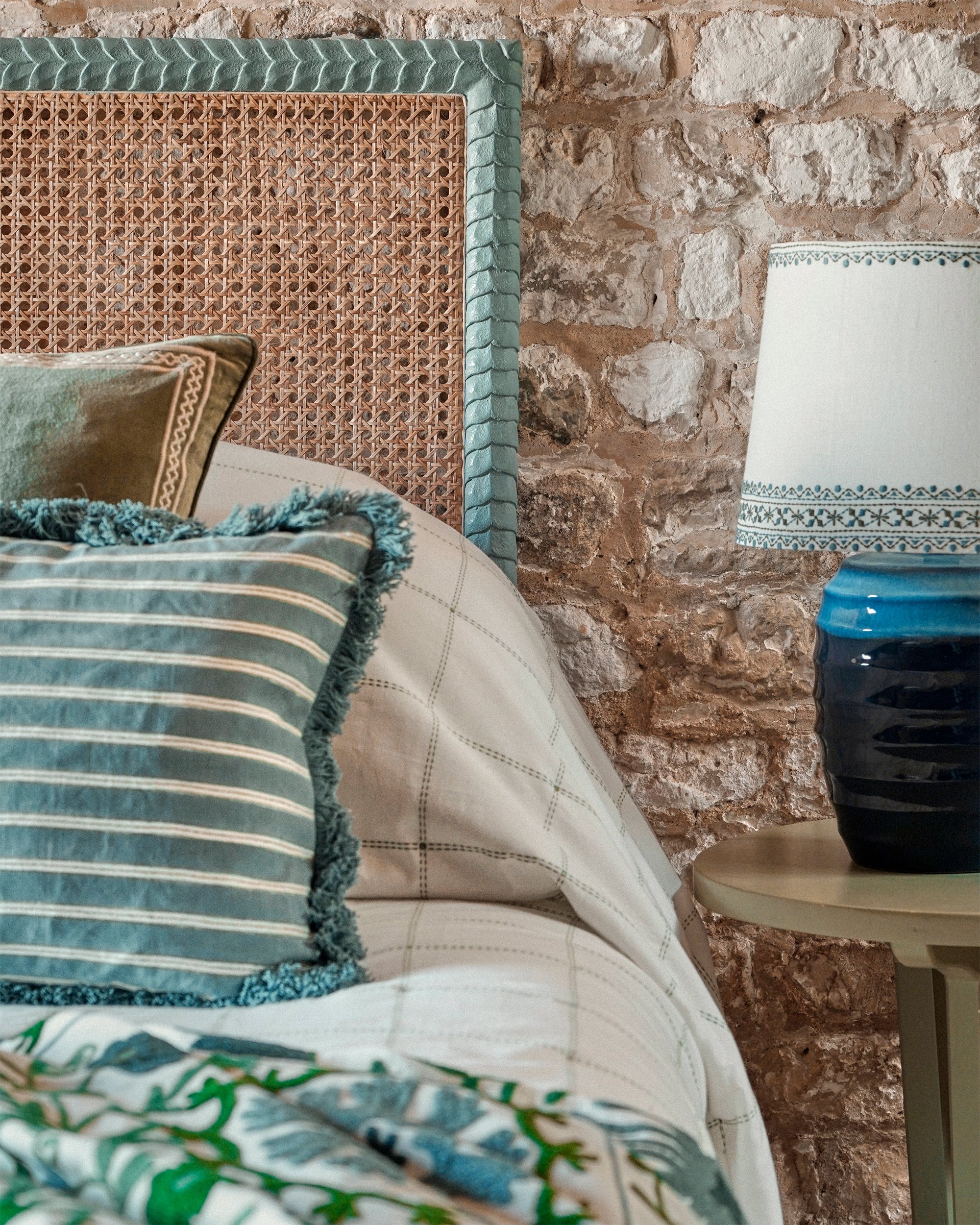 Cozy living room corner with a textured wall, wicker chair, and decorative pillows.