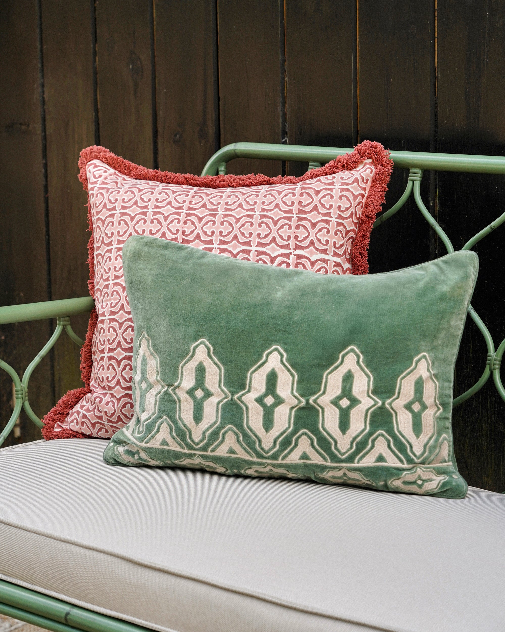 Two patterned cushions on a bench with a wooden background