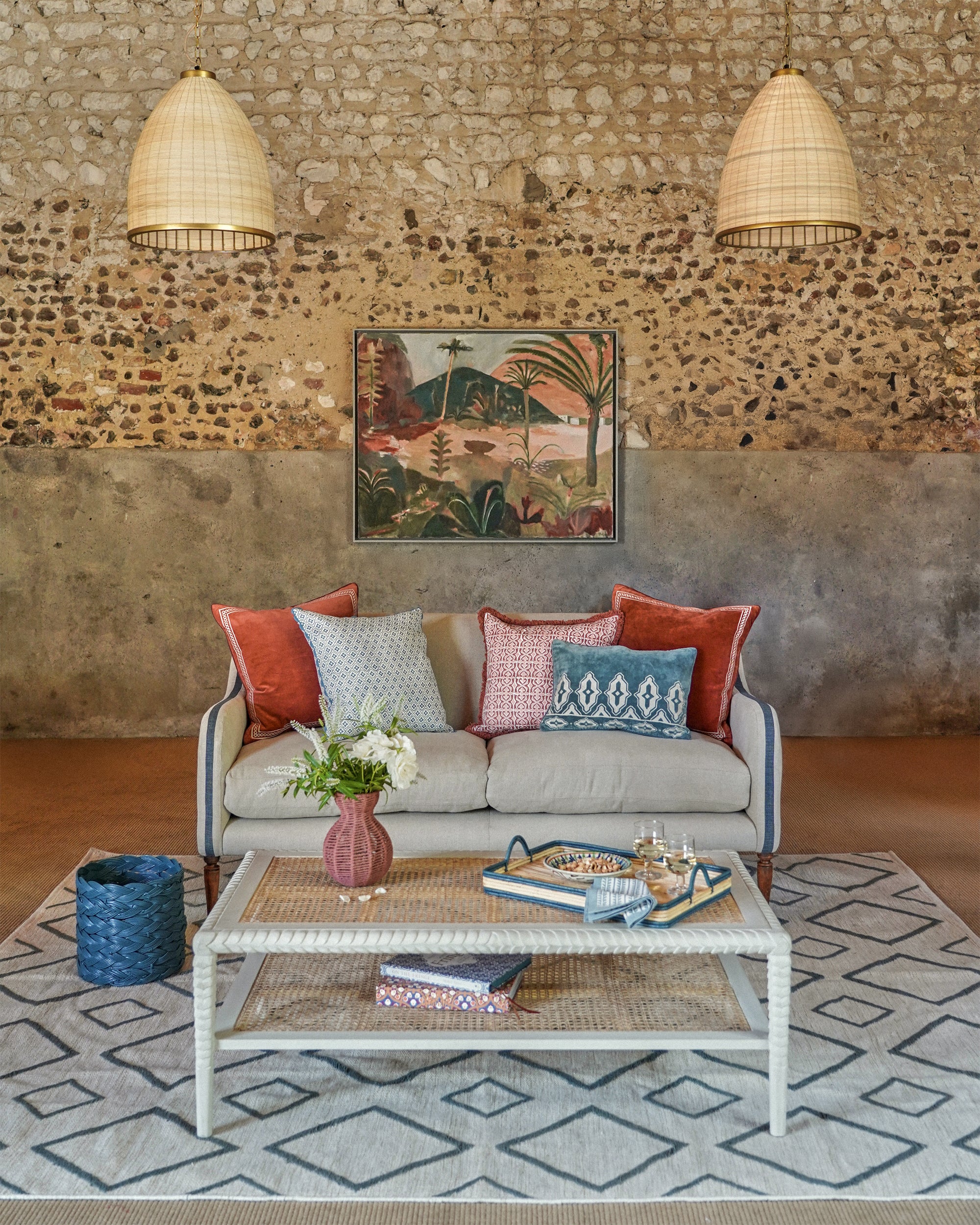 Living room with a stone wall, colourful cushions on a sofa, and a coffee table with decor items.