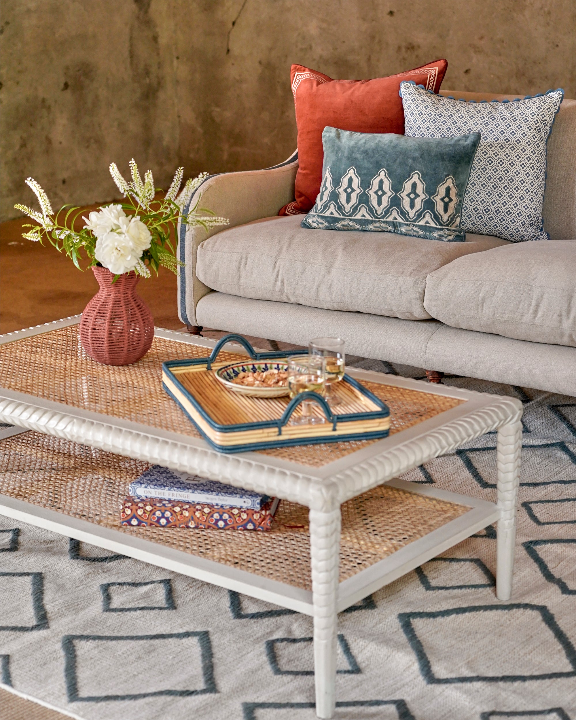 Living room with a beige sofa, wicker coffee table, and decorative pillows.
