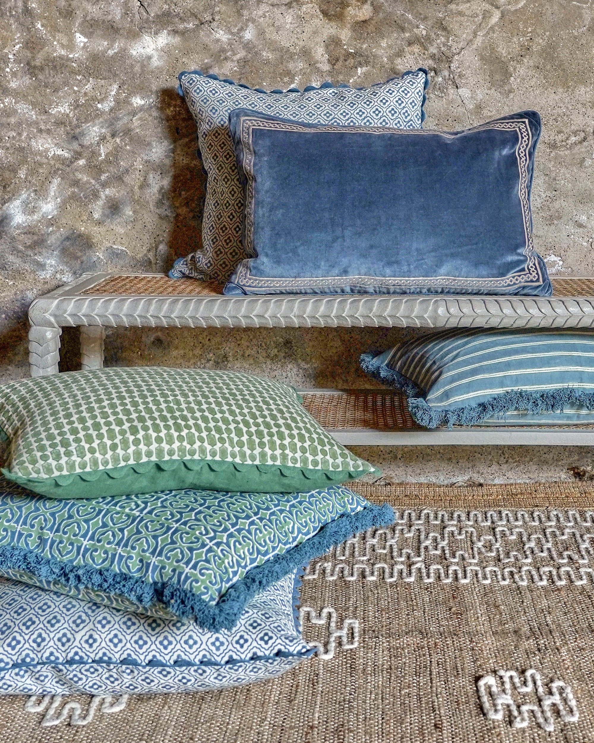 Decorative pillows in various patterns and colors on a textured surface.