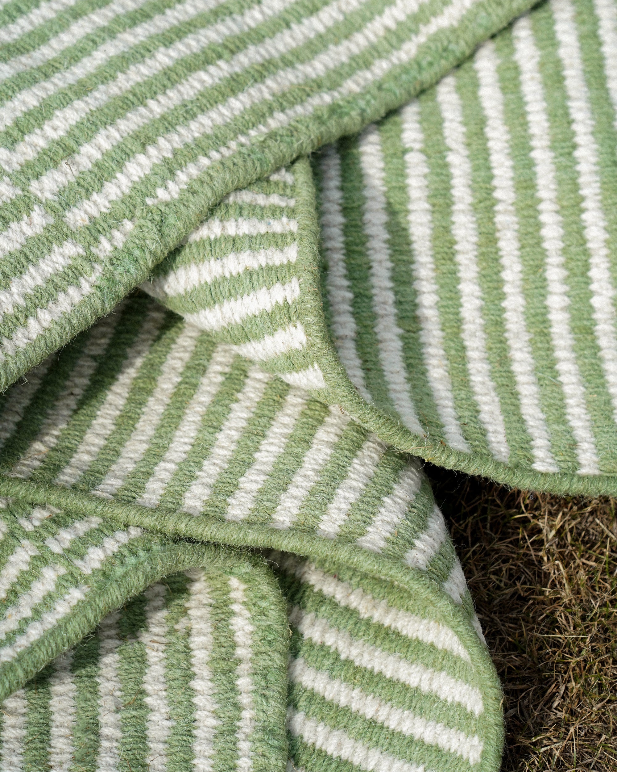 Close-up of green and white striped rug with a textured pattern.