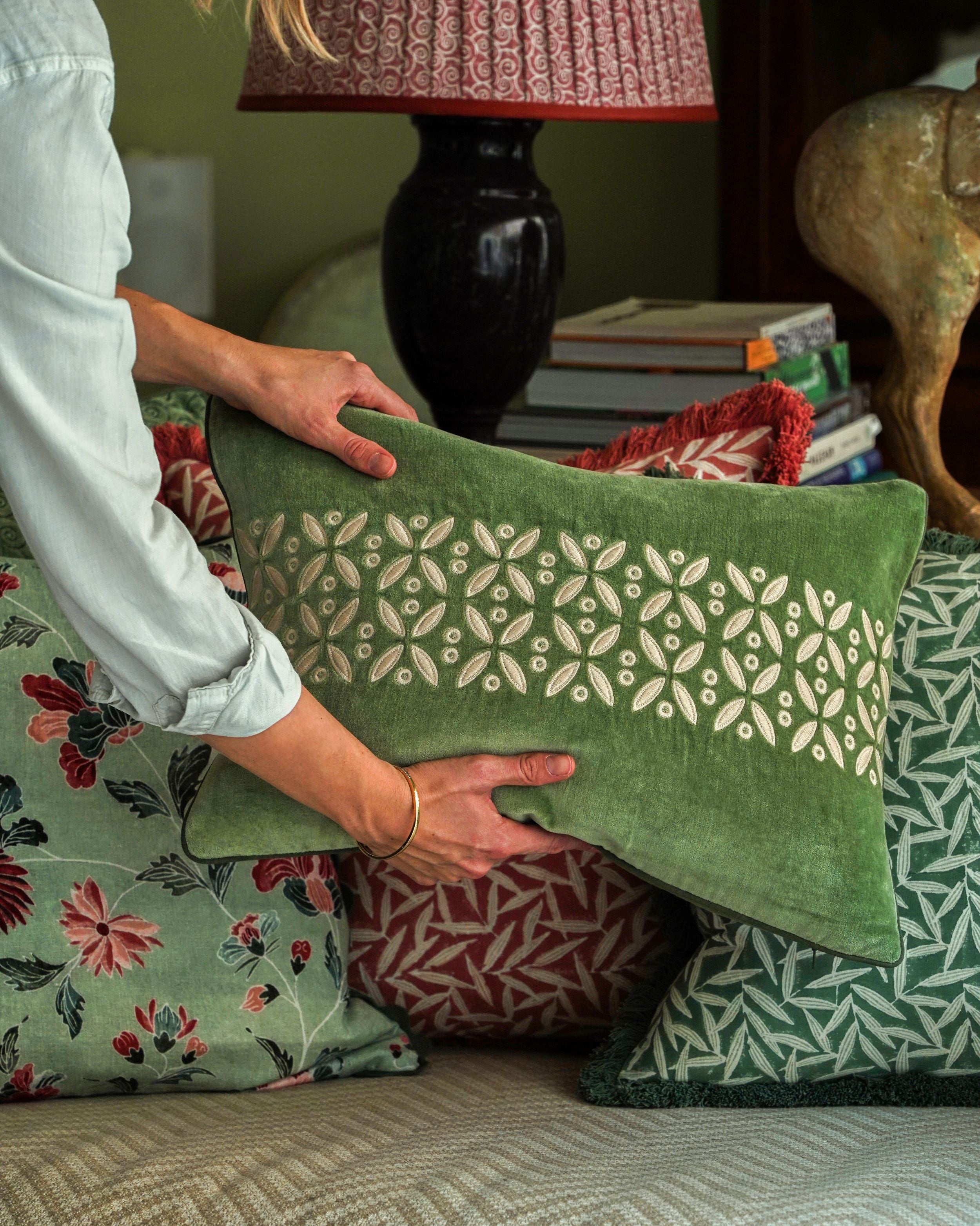 A model holds a green velvet cushion