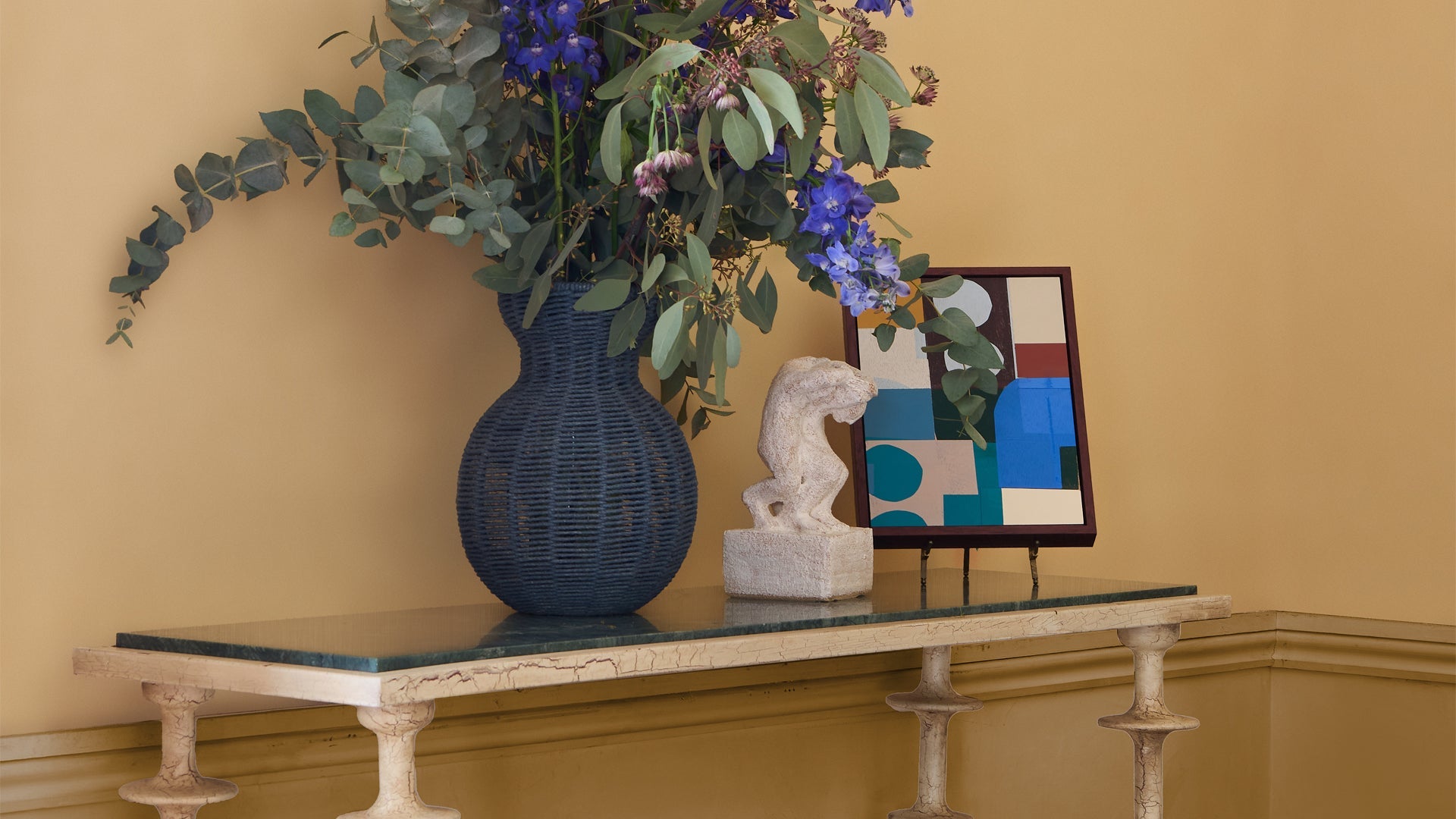 The gallery, artwork featured on wall behind a green and taupe dining set up